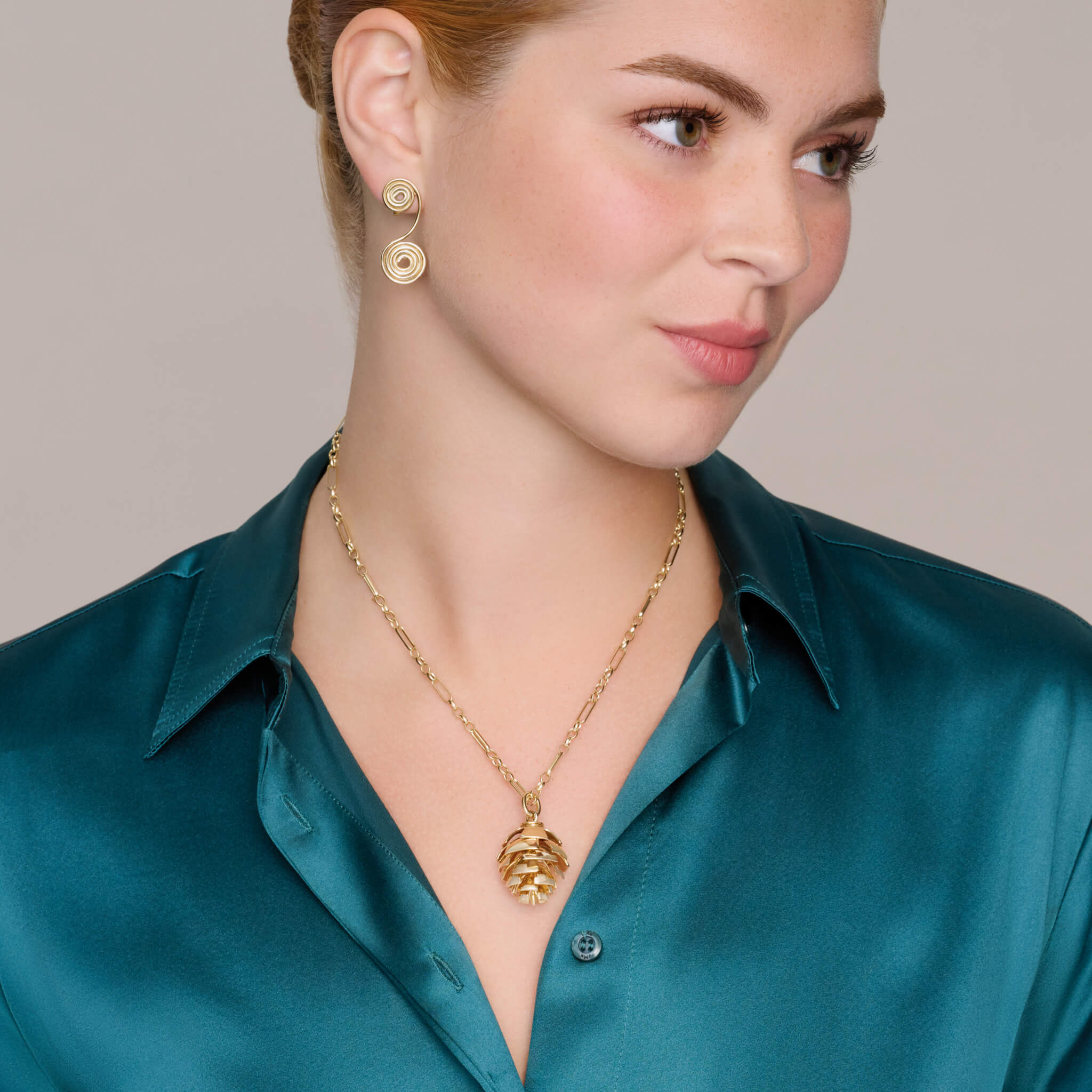 Model wearing a handcrafted yellow gold fir cone shaped necklace pendant with diamonds.