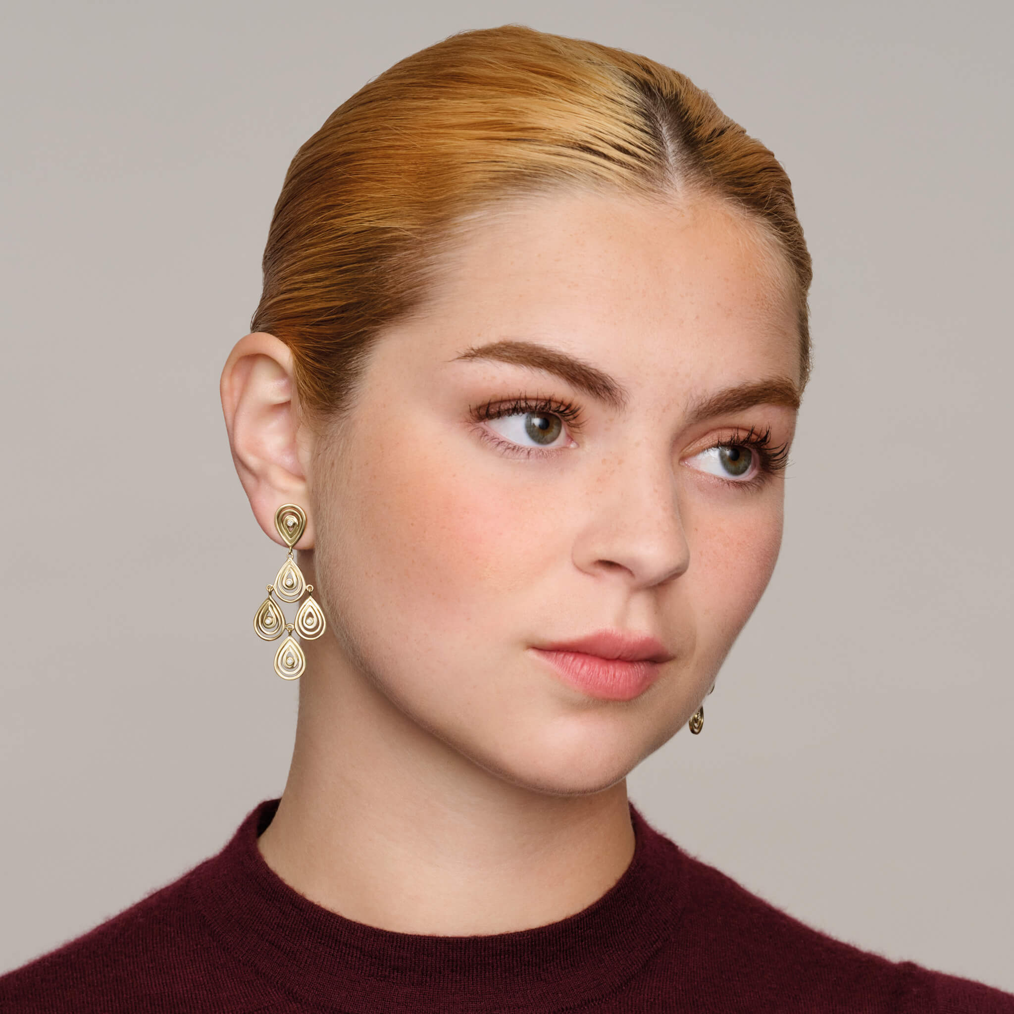 Model wears handcrafted 9ct yellow gold earrings with 5 diamonds in a cascading teardrop outline.