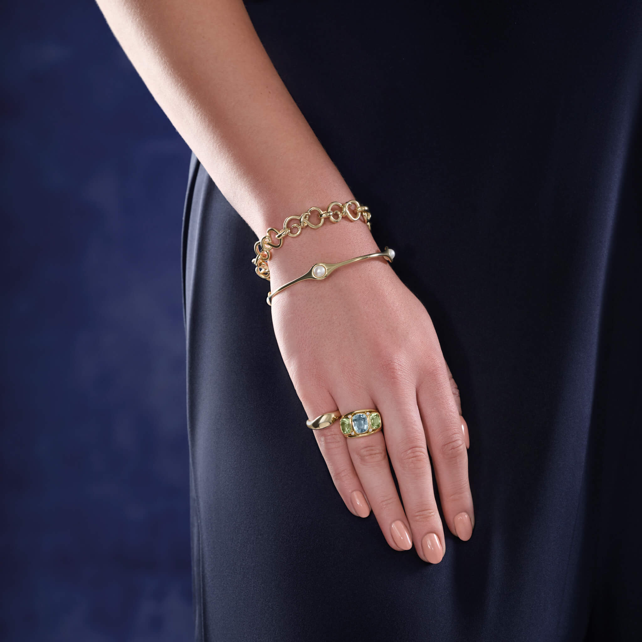 Model wearing a handcrafted 9ct yellow gold bracelet with interlocking golden swirls.