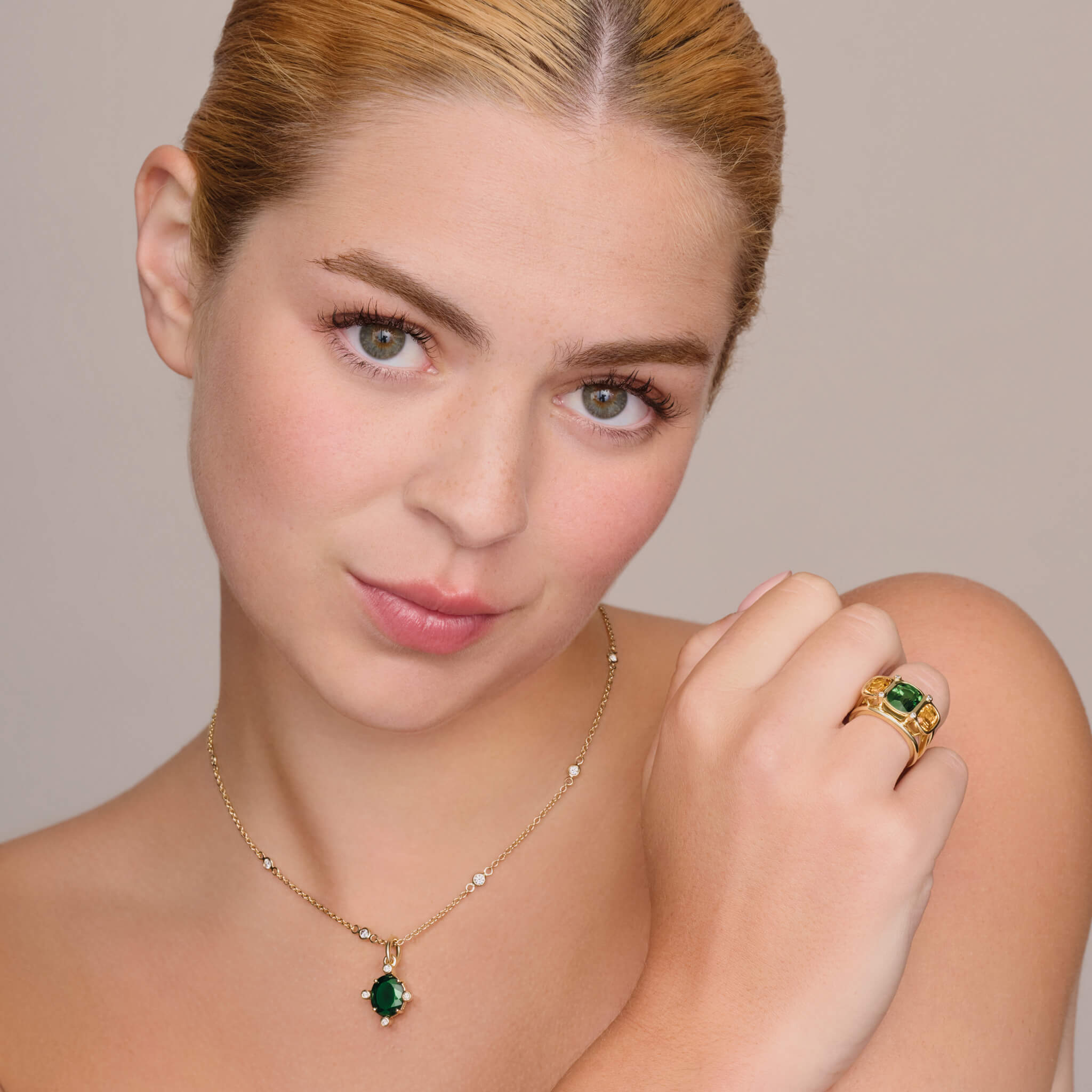 model wears handcrafted 18ct yellow gold ring featuring a central rectangular shaped green tourmaline, two citrines and diamonds.