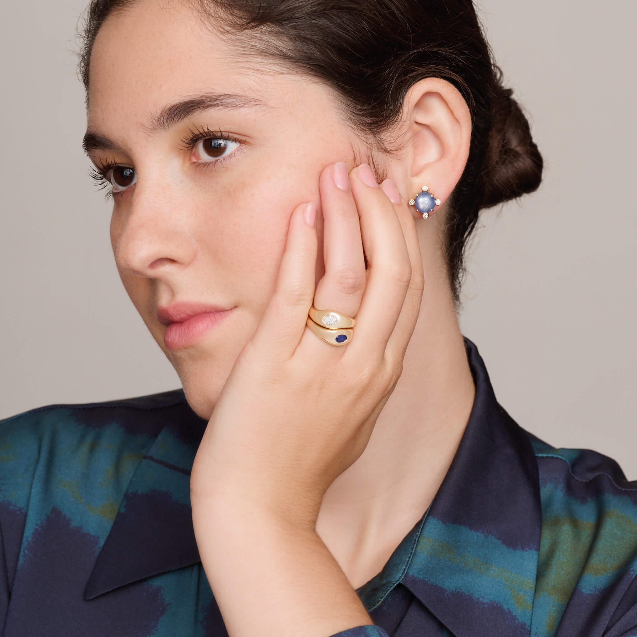 model wears handcrafted yellow gold ring with a slight teardrop design set with an oval facetted blue sapphire.