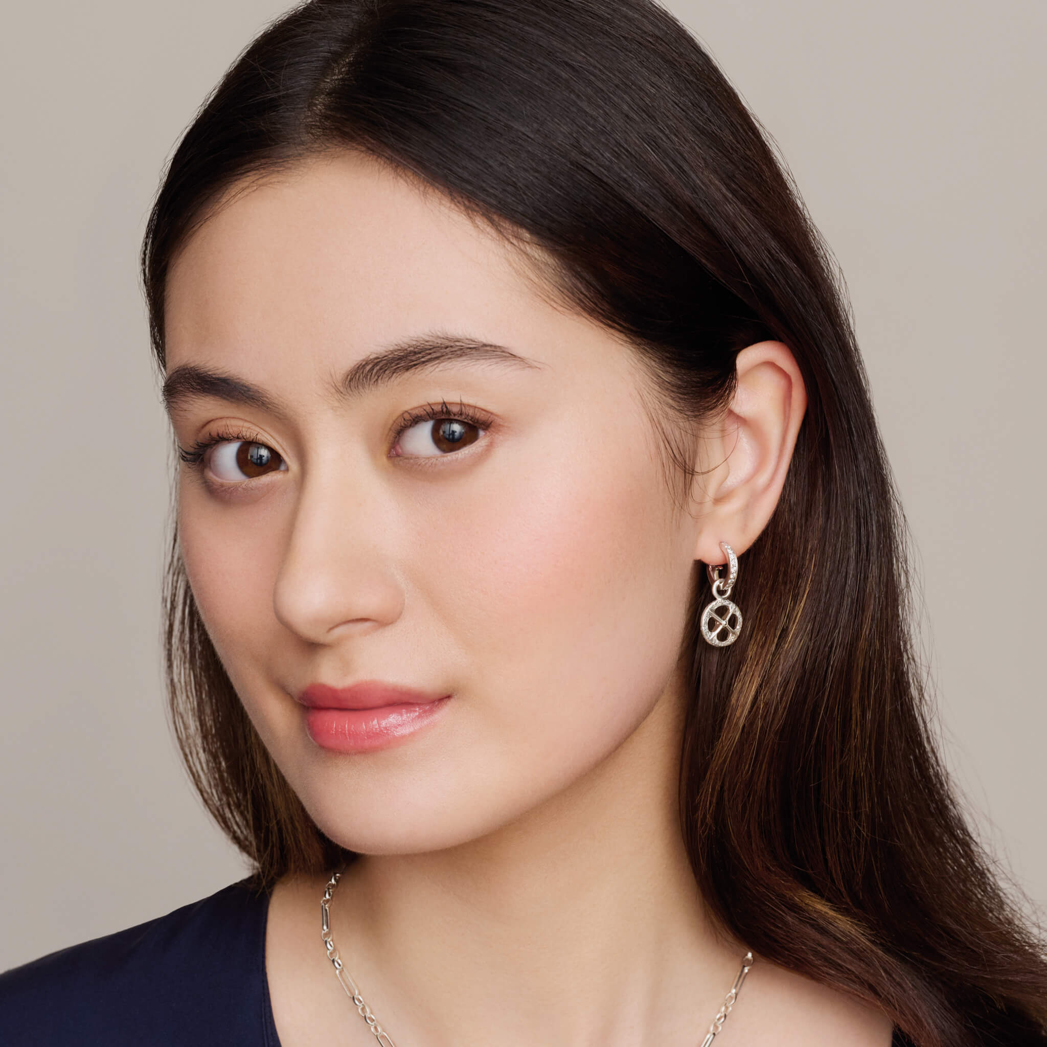Model wearing handcrafted silver earring drops with a circular motif and a cross in the middle.