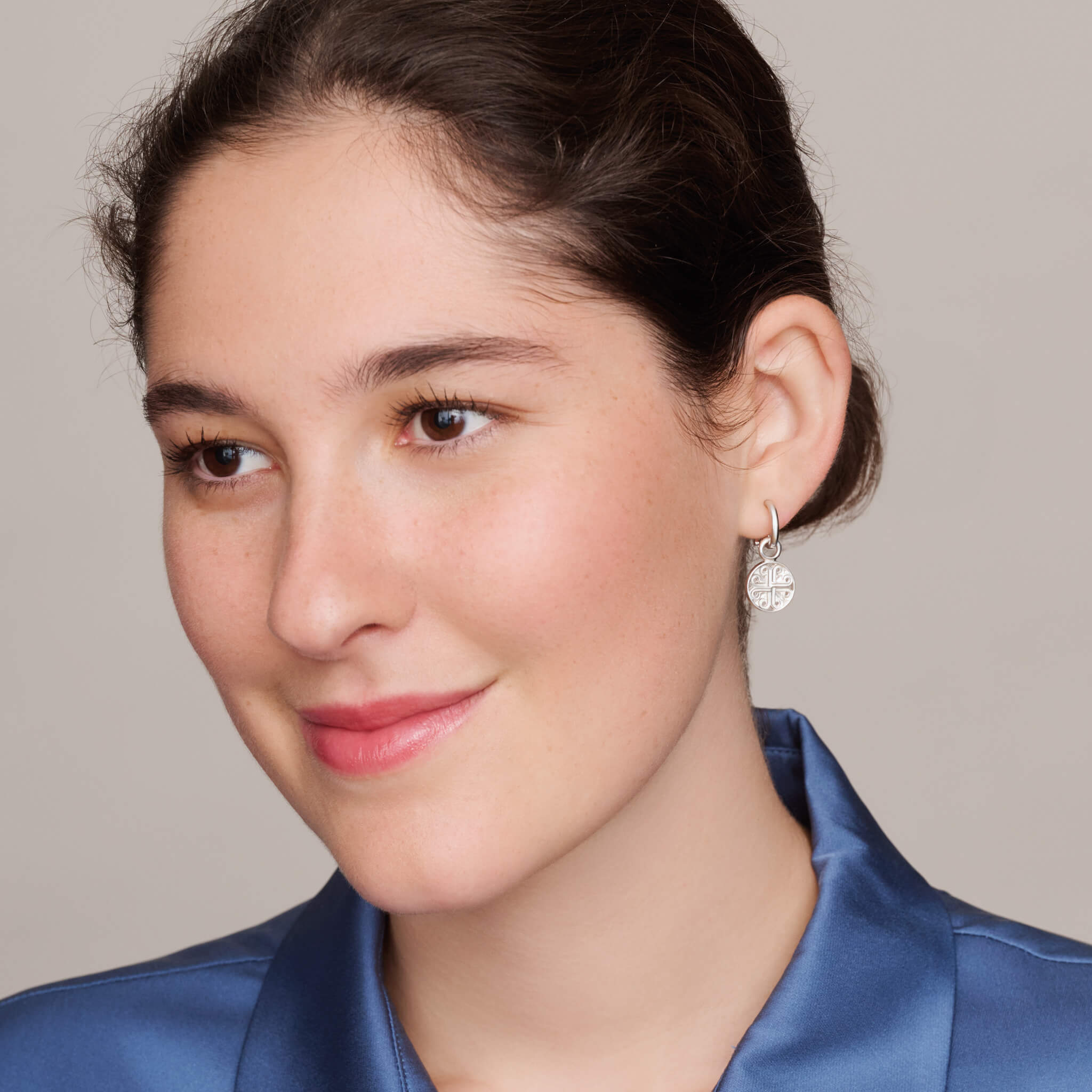 model wearing handcrafted interchangeable silver circular earring drops with a cross-like motif in the centre.