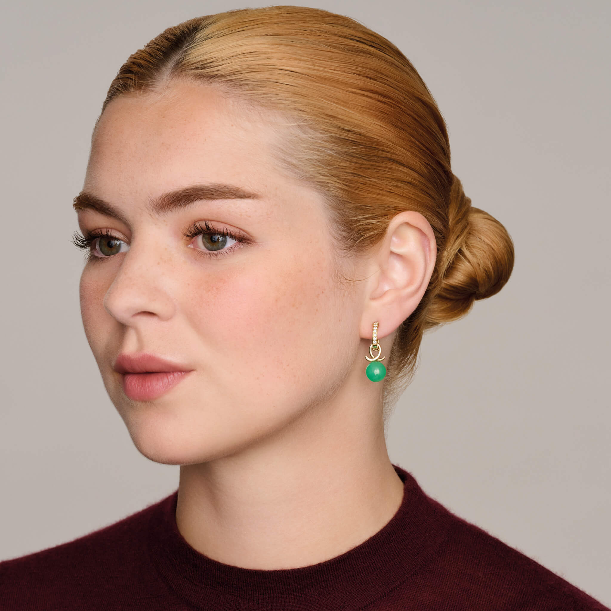 model wears handcrafted 9ct yellow gold earring drops with round fine green chrysoprase and an oval loop shape crossing over.