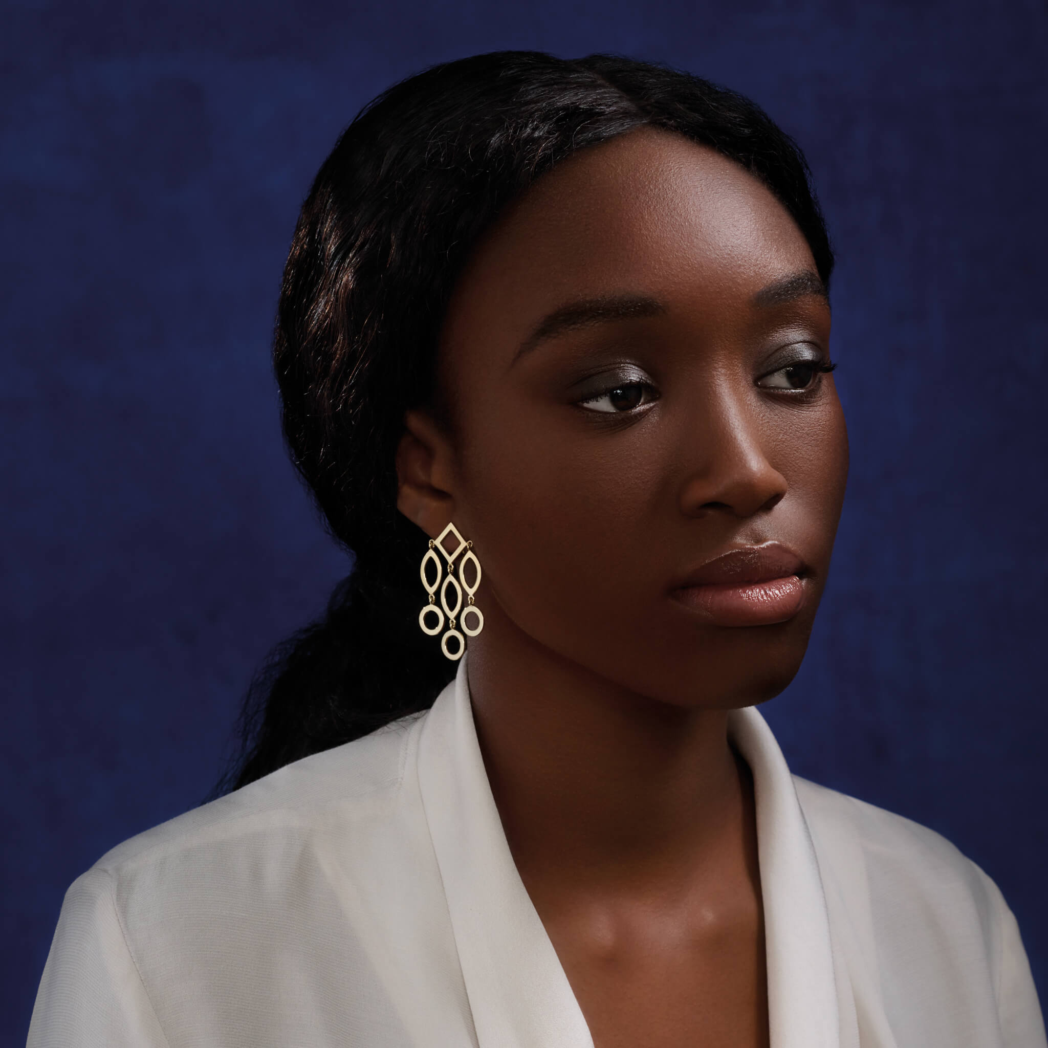 Model wears handcrafted 9ct yellow gold earrings featuring circular and oval shapes.