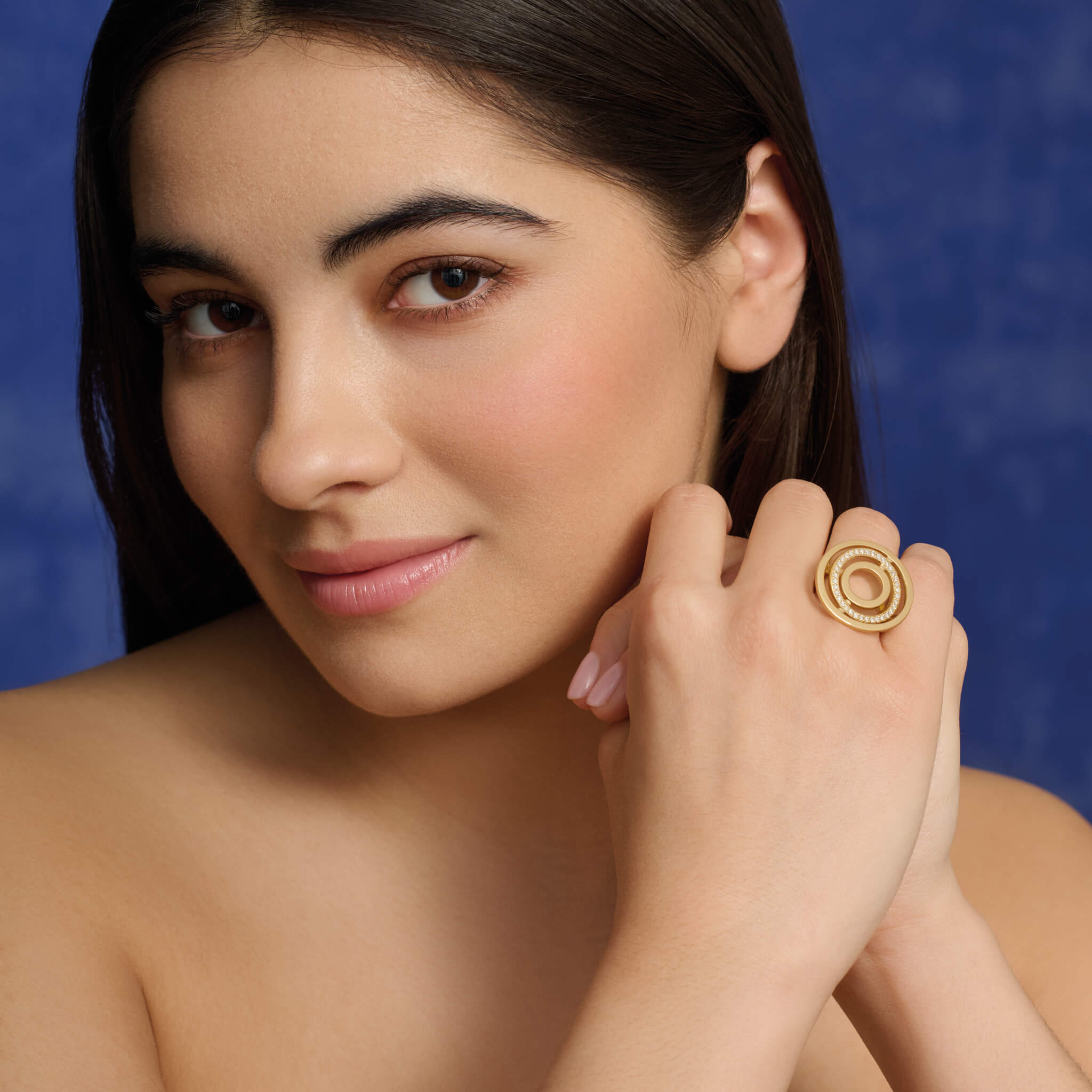 Model wears handcrafted 18ct yellow gold cocktail ring featuring three concentric circles with movement with diamond pavé.
