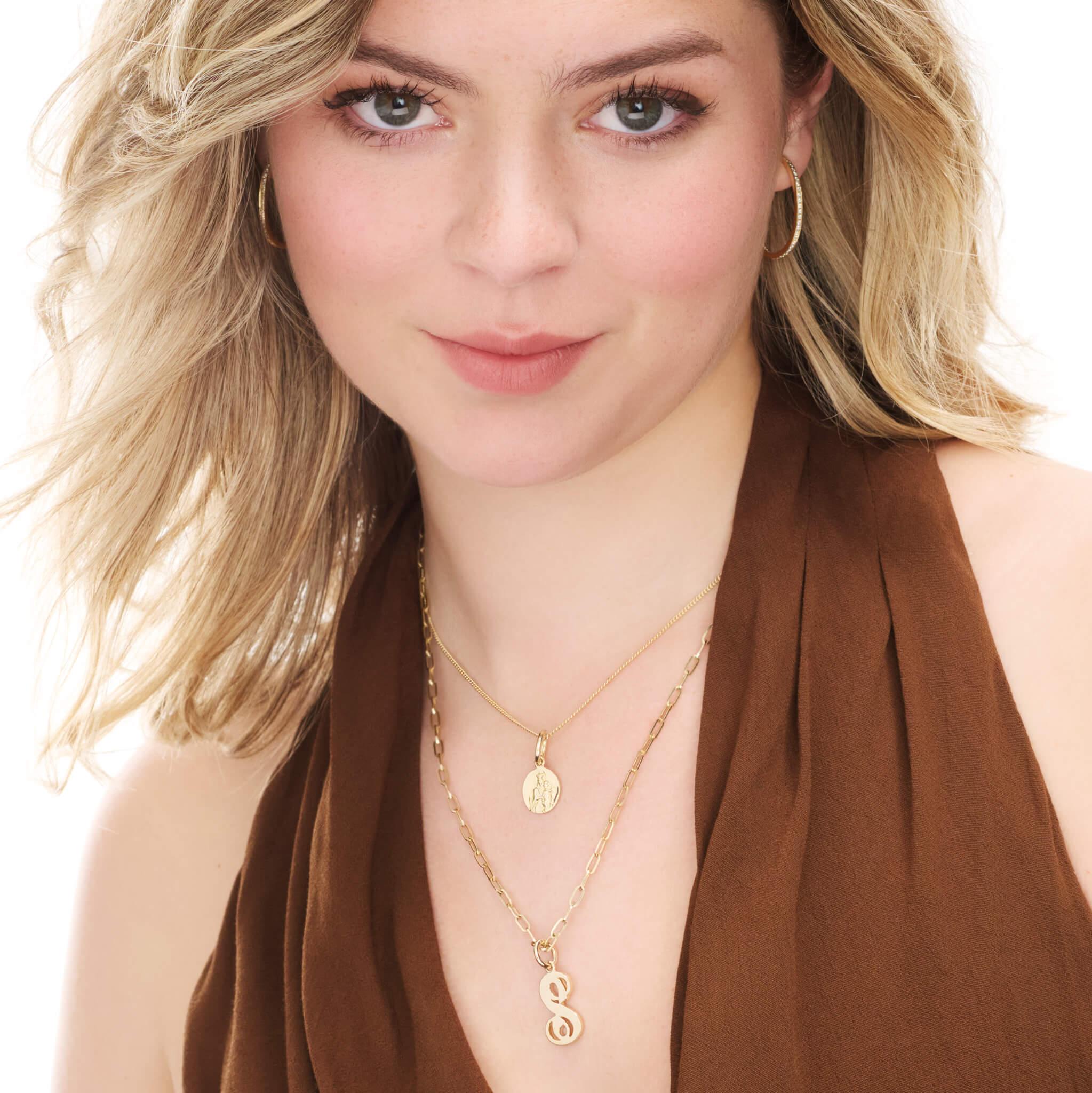 Model wearing handcrafted round yellow gold necklace pendant featuring an engraving of Saint Maria, hanging from a gold chain.