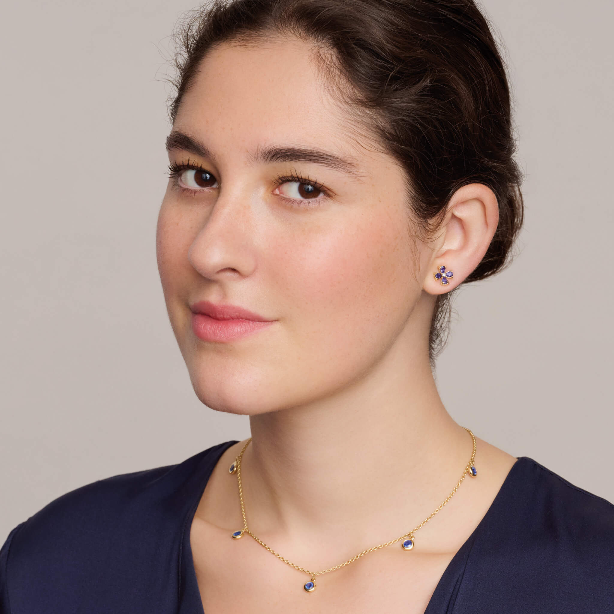 model wearing handcrafted yellow gold necklace with five round blue sapphire drops, birthstone of September.