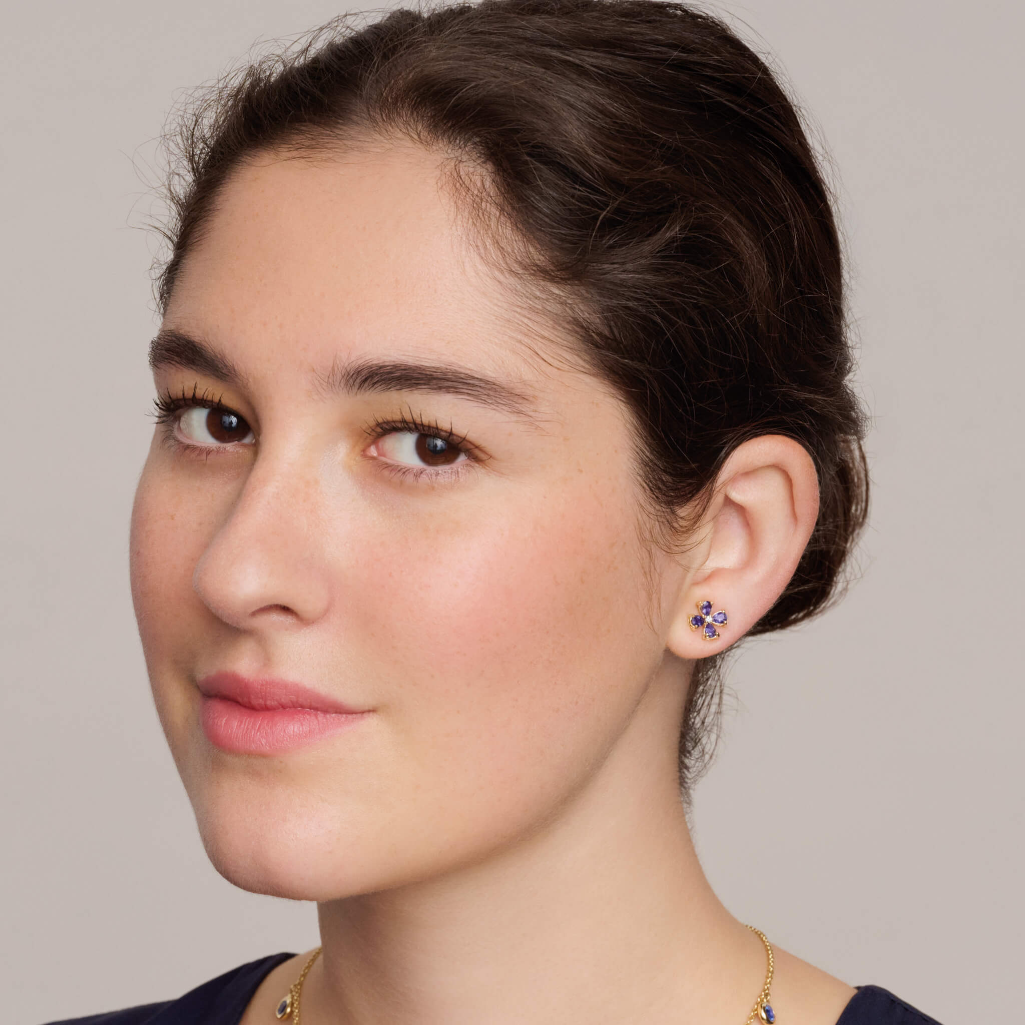 Model wearing handcrafted four-leaf clover earring studs in precious metal with precious stones.