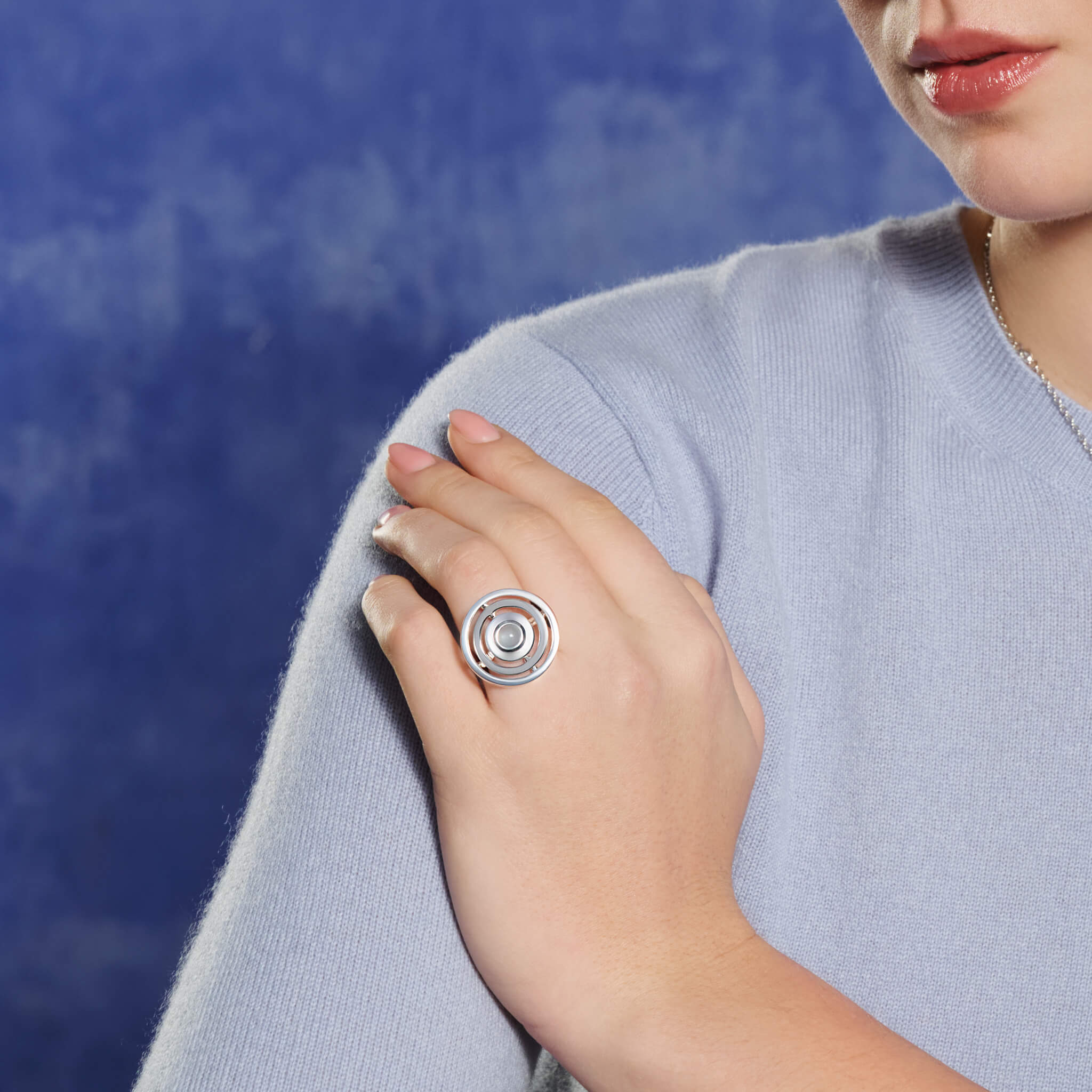 Model wears handcrafted sterling silver cocktail ring featuring three concentric circles with movement and a central cabochon blue aquamarine.