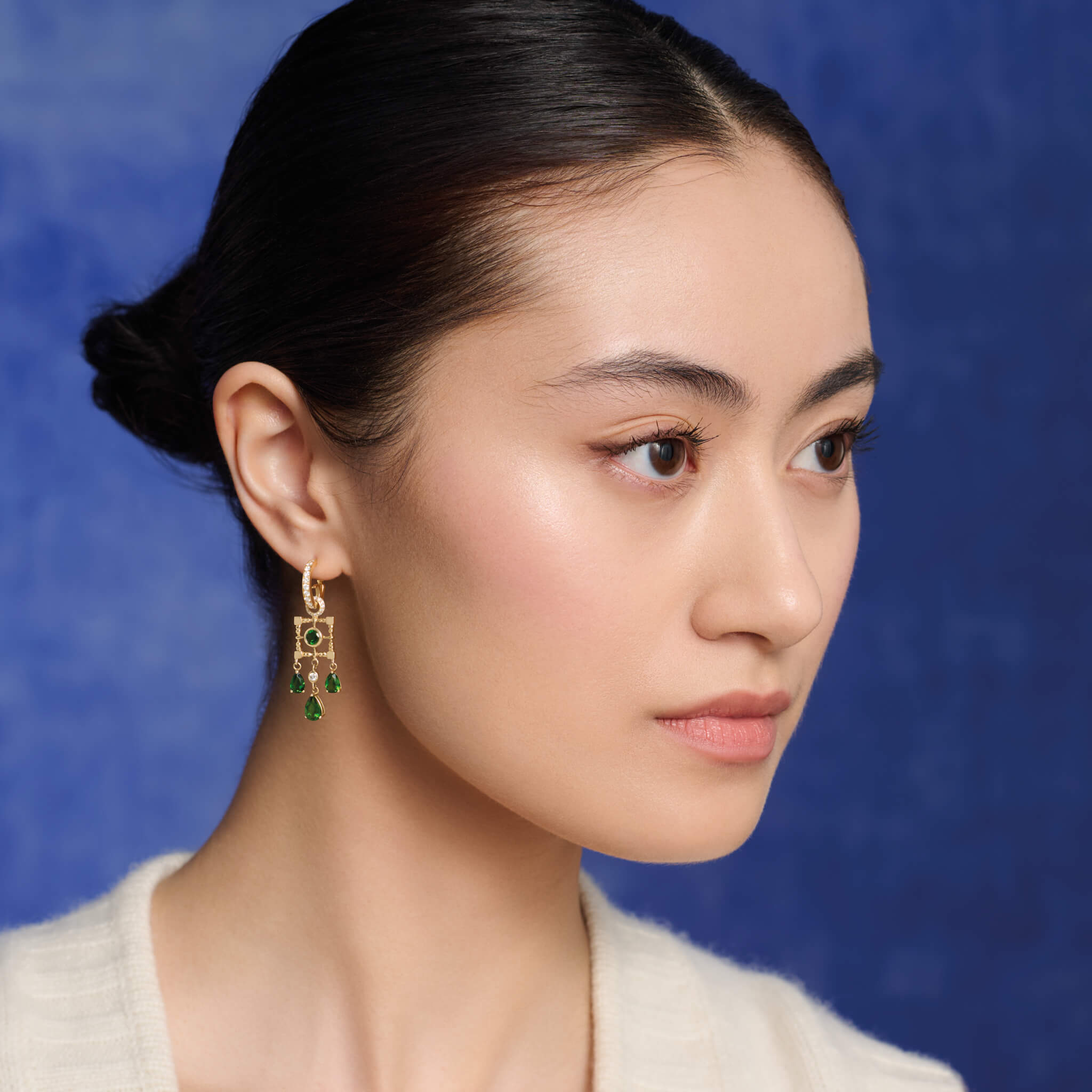 Model wearing handcrafted earring drops in 9ct yellow gold featuring a teardrop-shaped design with facetted chrome diopside and diamond.