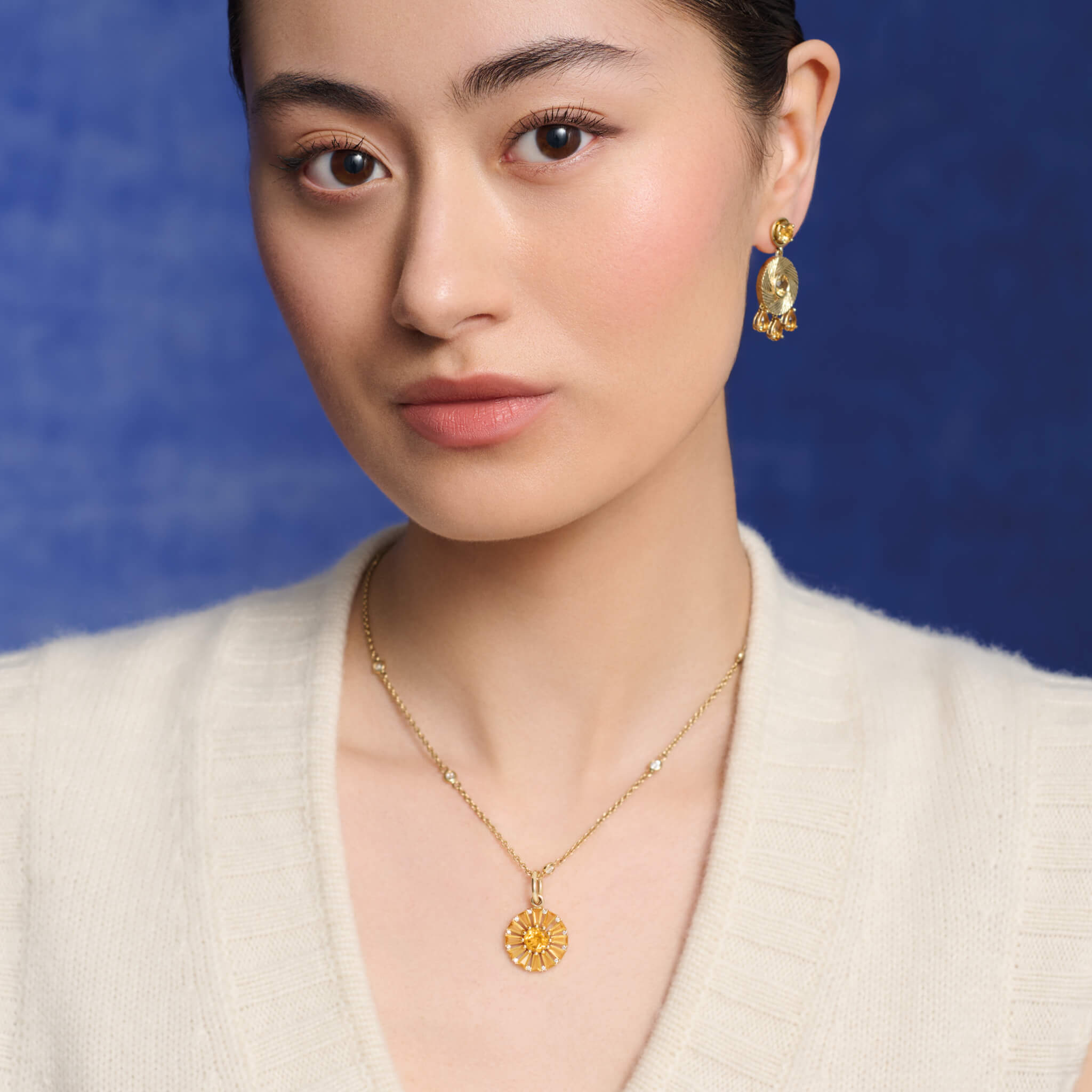 Model wears handcrafted yellow gold necklace pendant featuring a circular arrangement of citrine and diamond, birthstone of November.