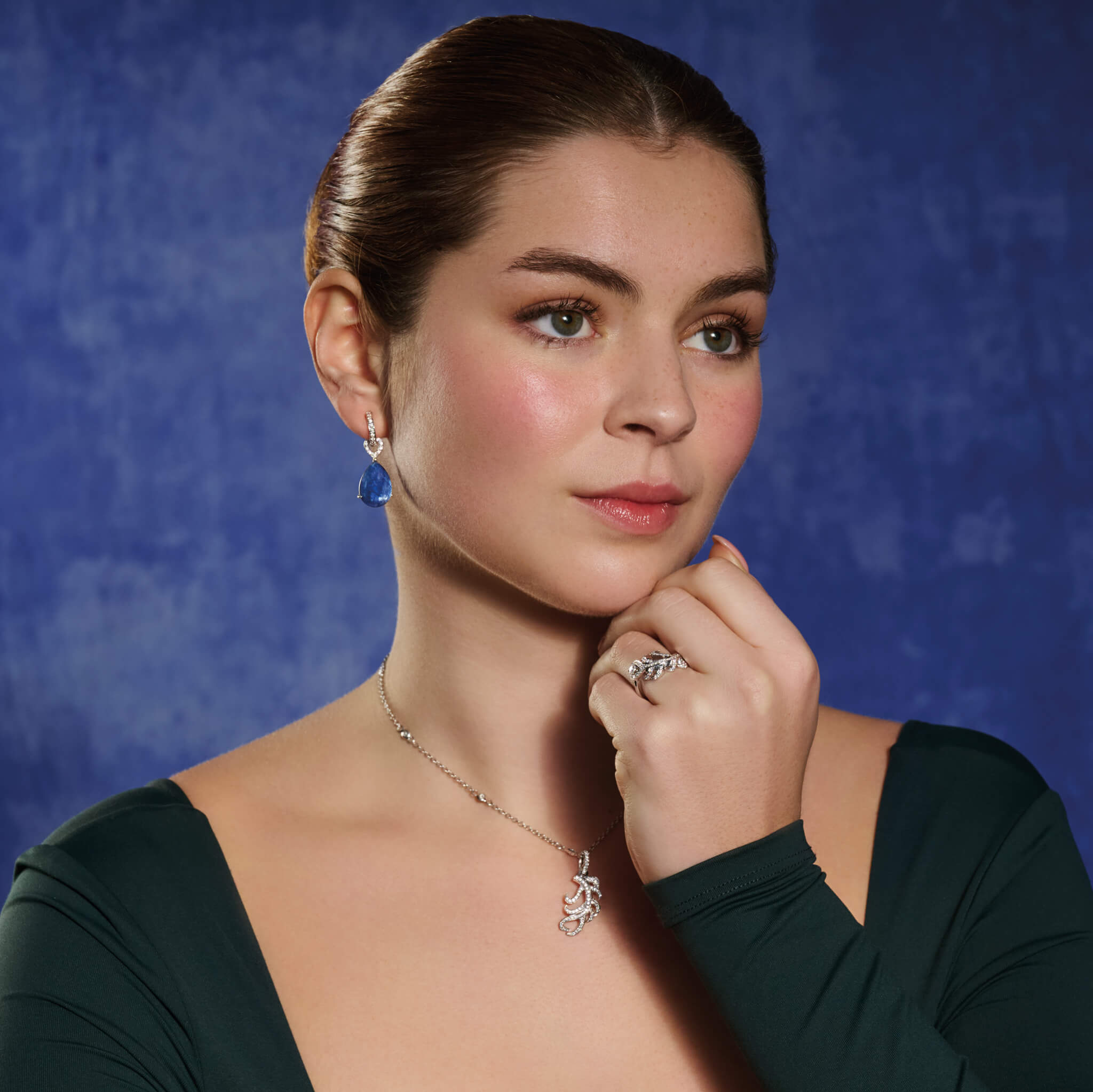 Model wears handcrafted necklace pendant in the shape of a feather plume in 18ct white gold with diamond pavé.