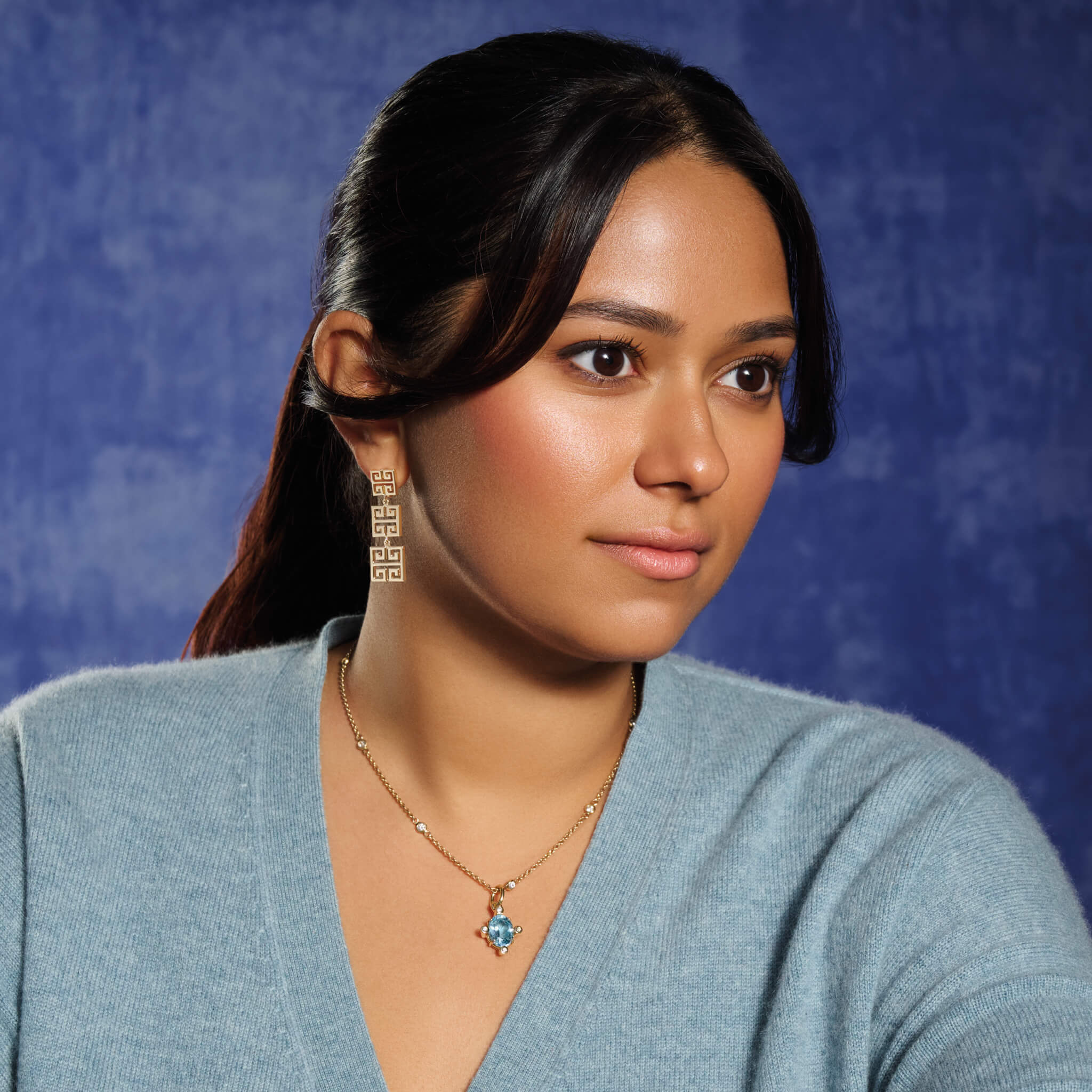Model wears handcrafted Compass medium necklace pendant in yellow gold with blue topaz set with four diamonds.