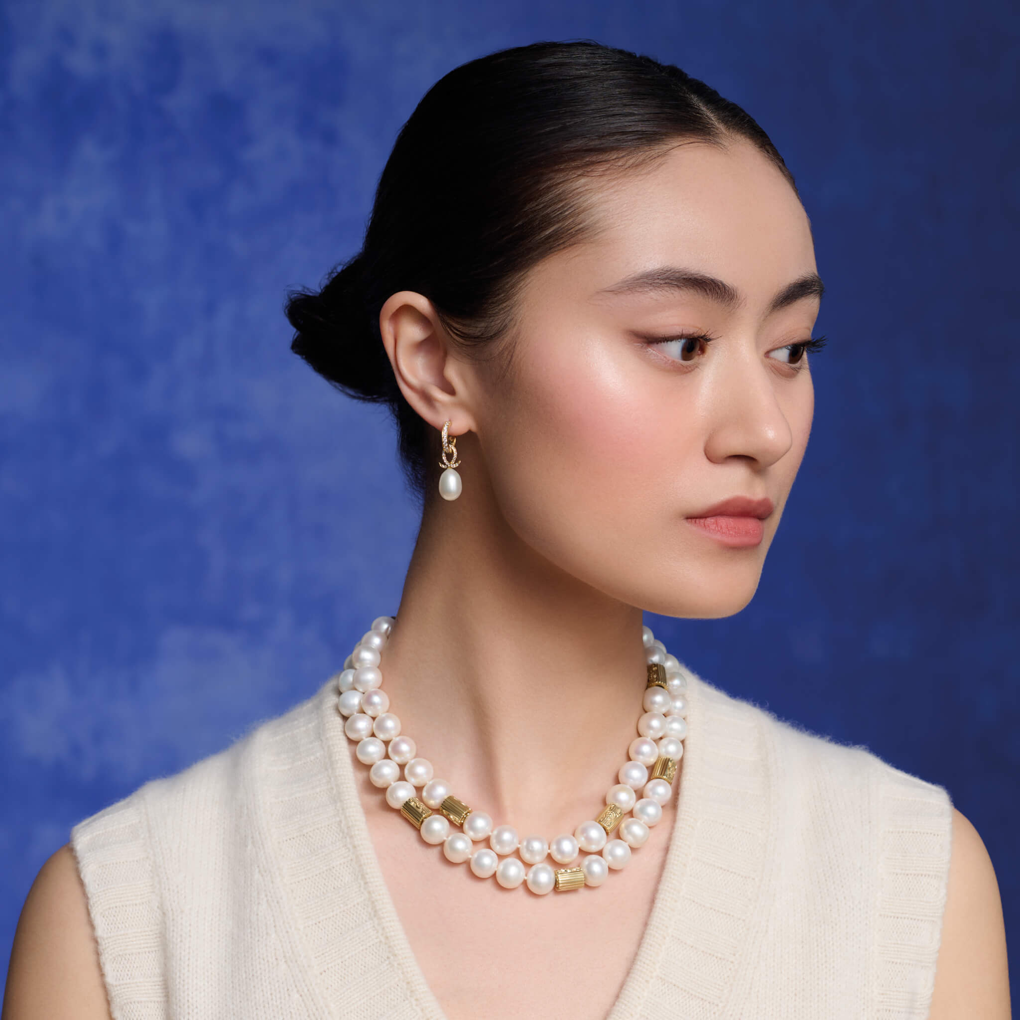 Model wears handcrafted 18ct yellow gold earring drops with oval pearl and diamond pave oval loop shape.