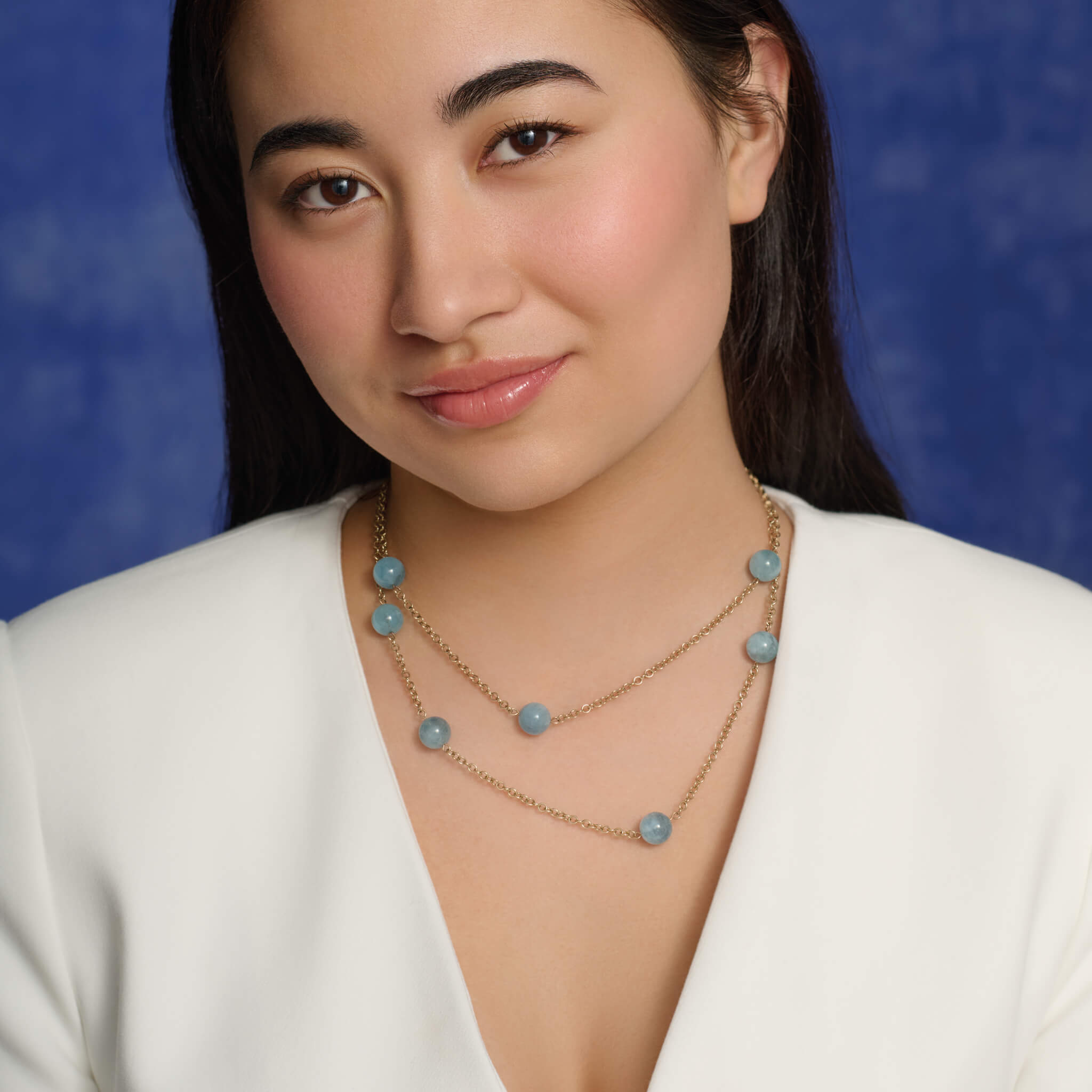 Model wears handcrafted 9ct yellow gold necklace featuring six aquamarine beads on a yellow gold chain.