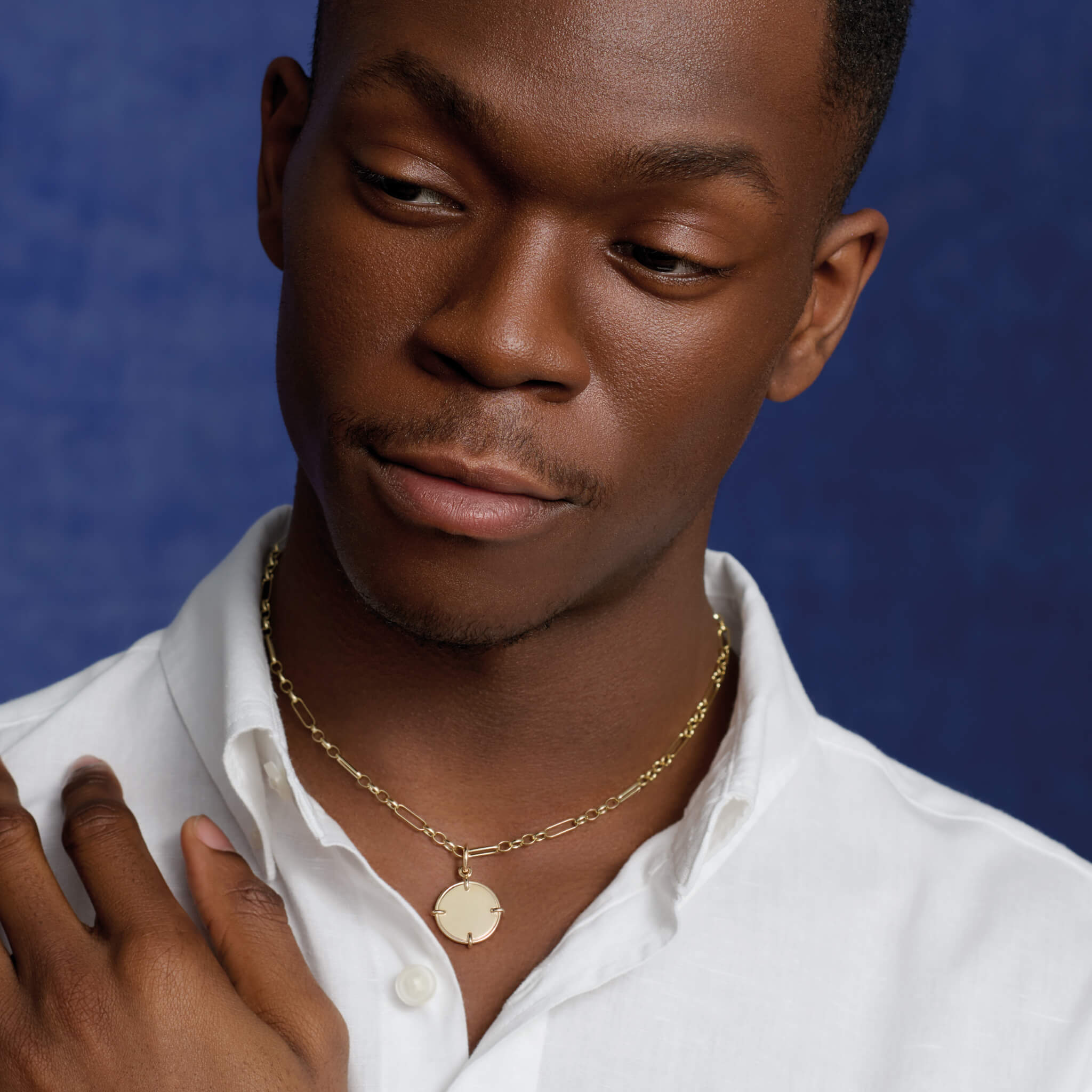 Model wears handcrafted necklace pendant in precious metal featuring a round shape with four points.
