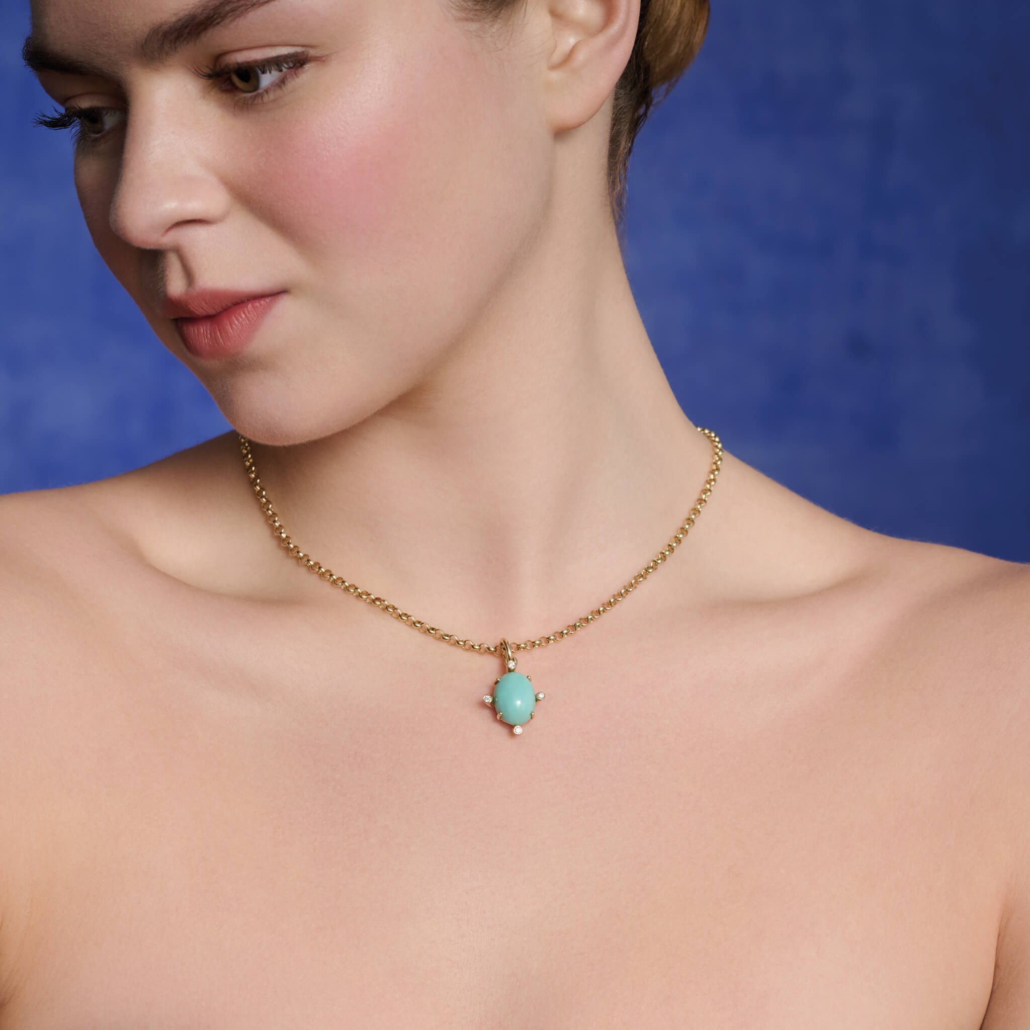 Model wears handcrafted 9ct yellow gold pendant with oval turquoise gemstone set with four round diamonds.