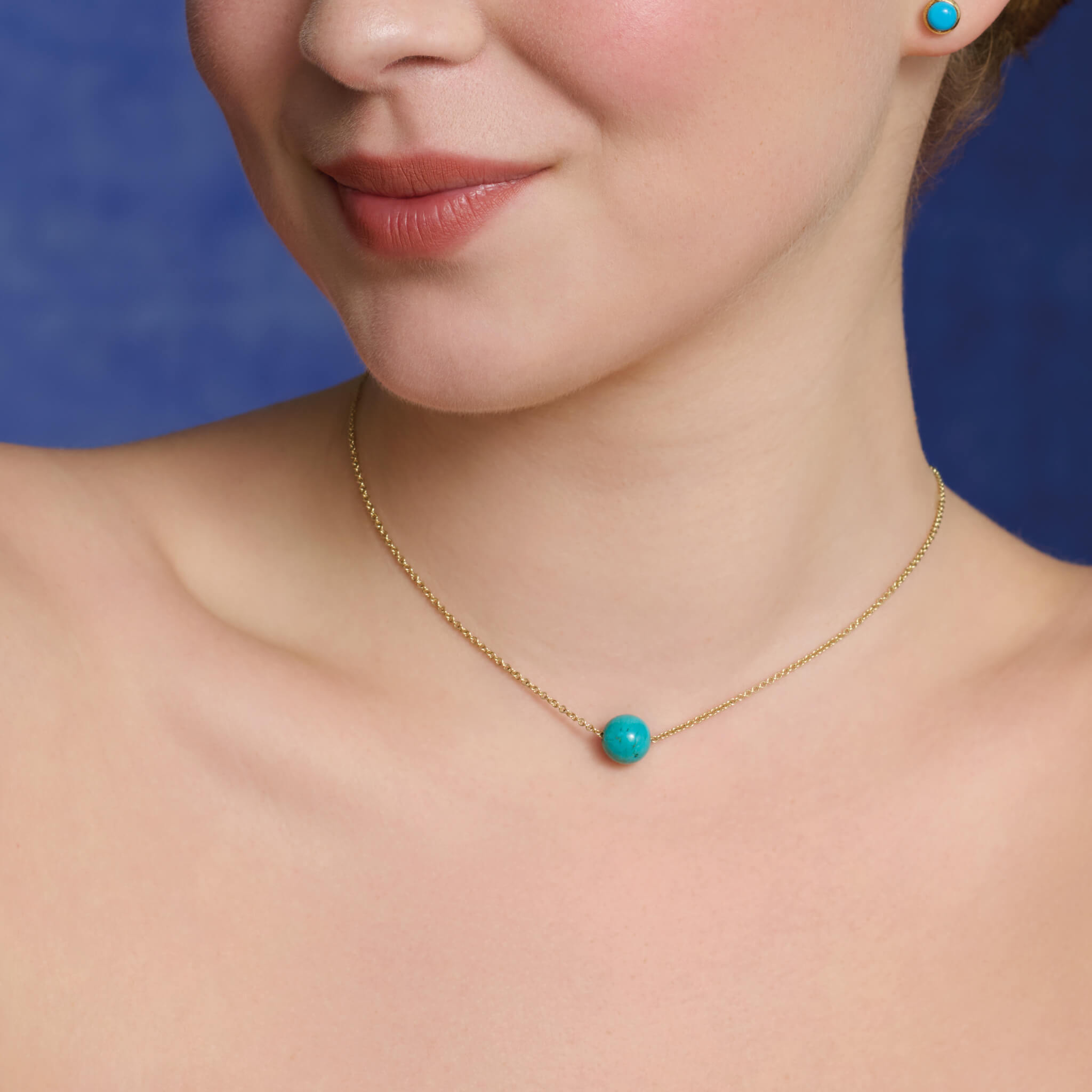 Model wears the handcrafted Pelota necklace in 9ct yellow gold with turquoise.