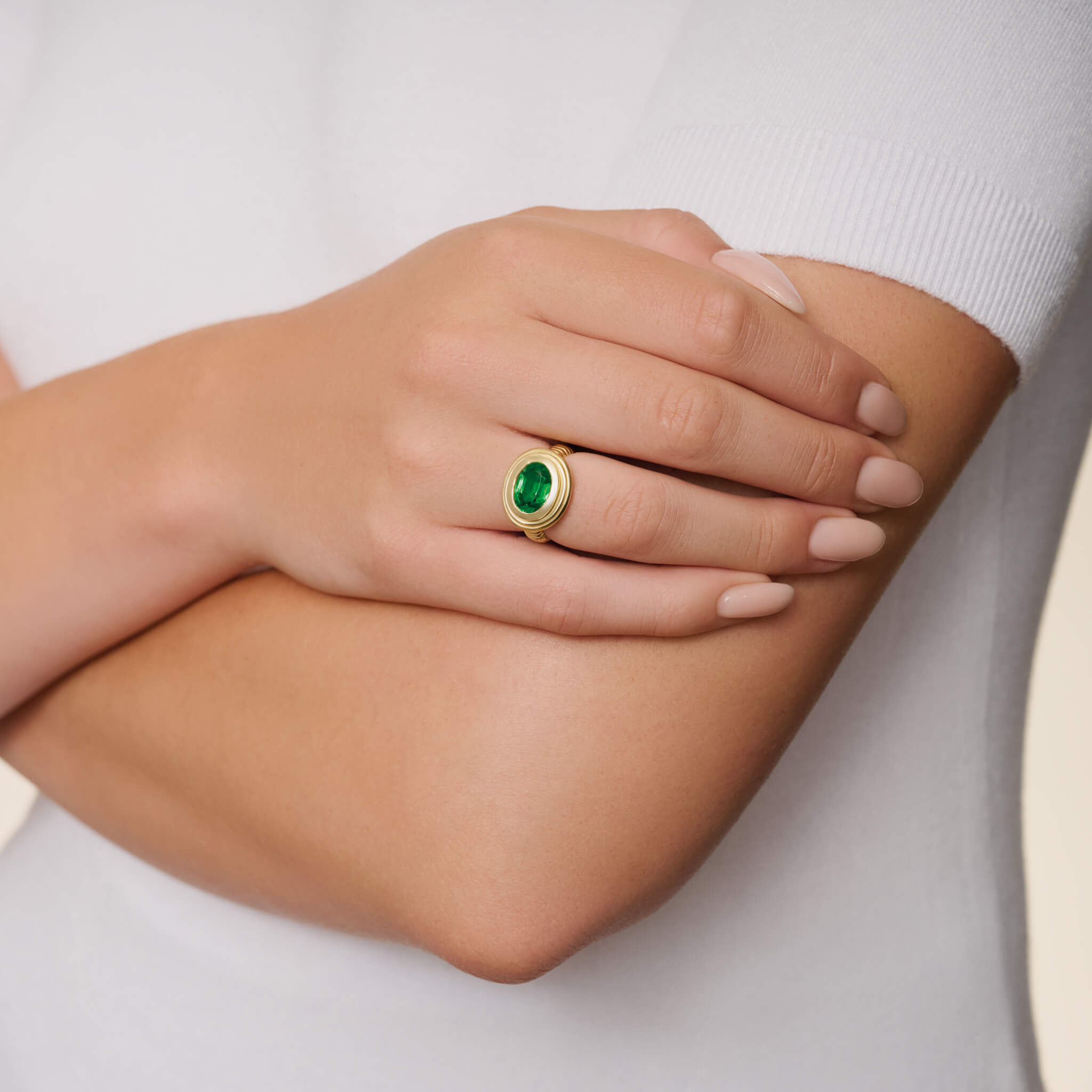 model wears handcrafted 18ct yellow gold ring featuring a prominent oval tsavorite garnet. 