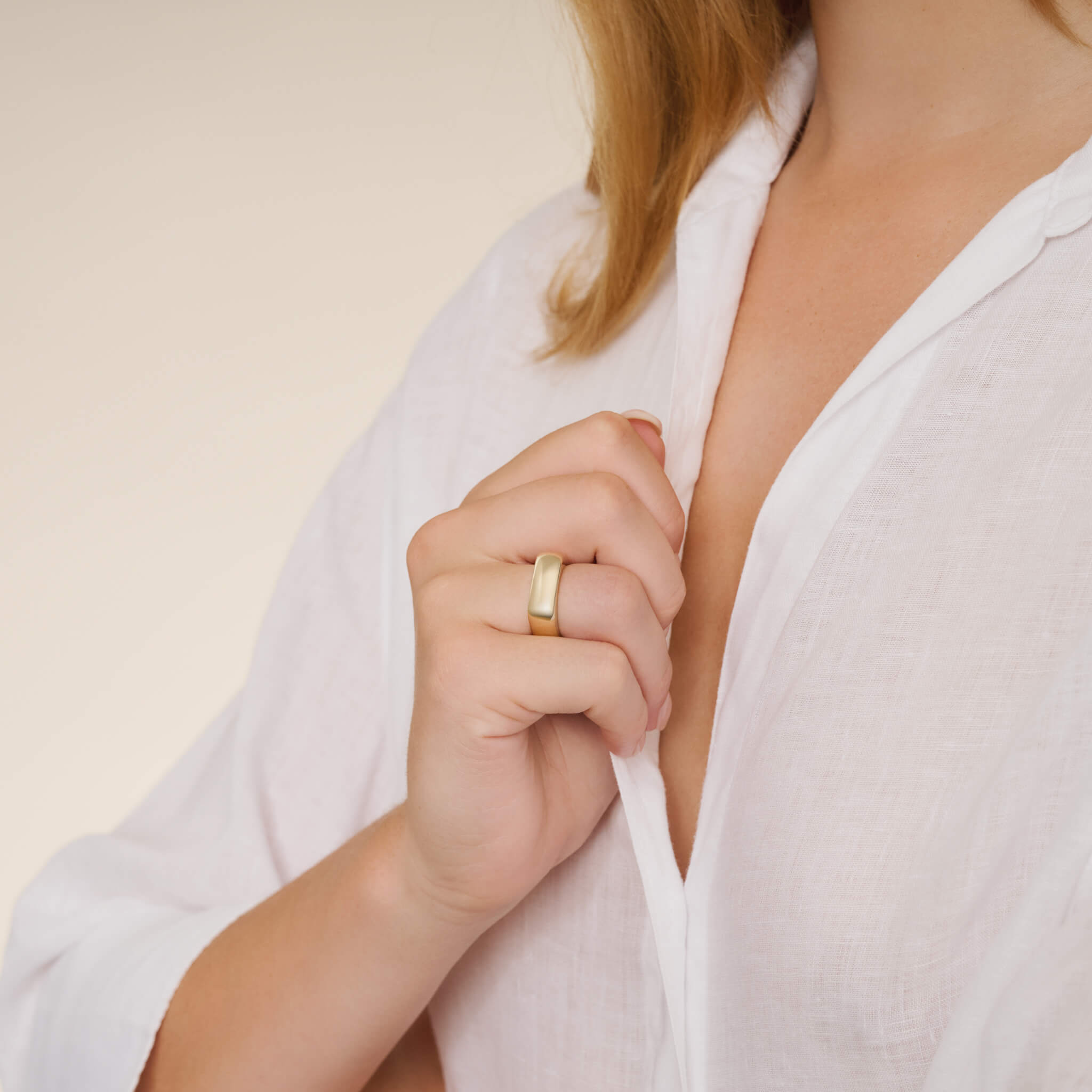 Model wears handcrafted square-shaped ring in 9ct yellow gold with rounded corners inspired by traditional Greek architecture.