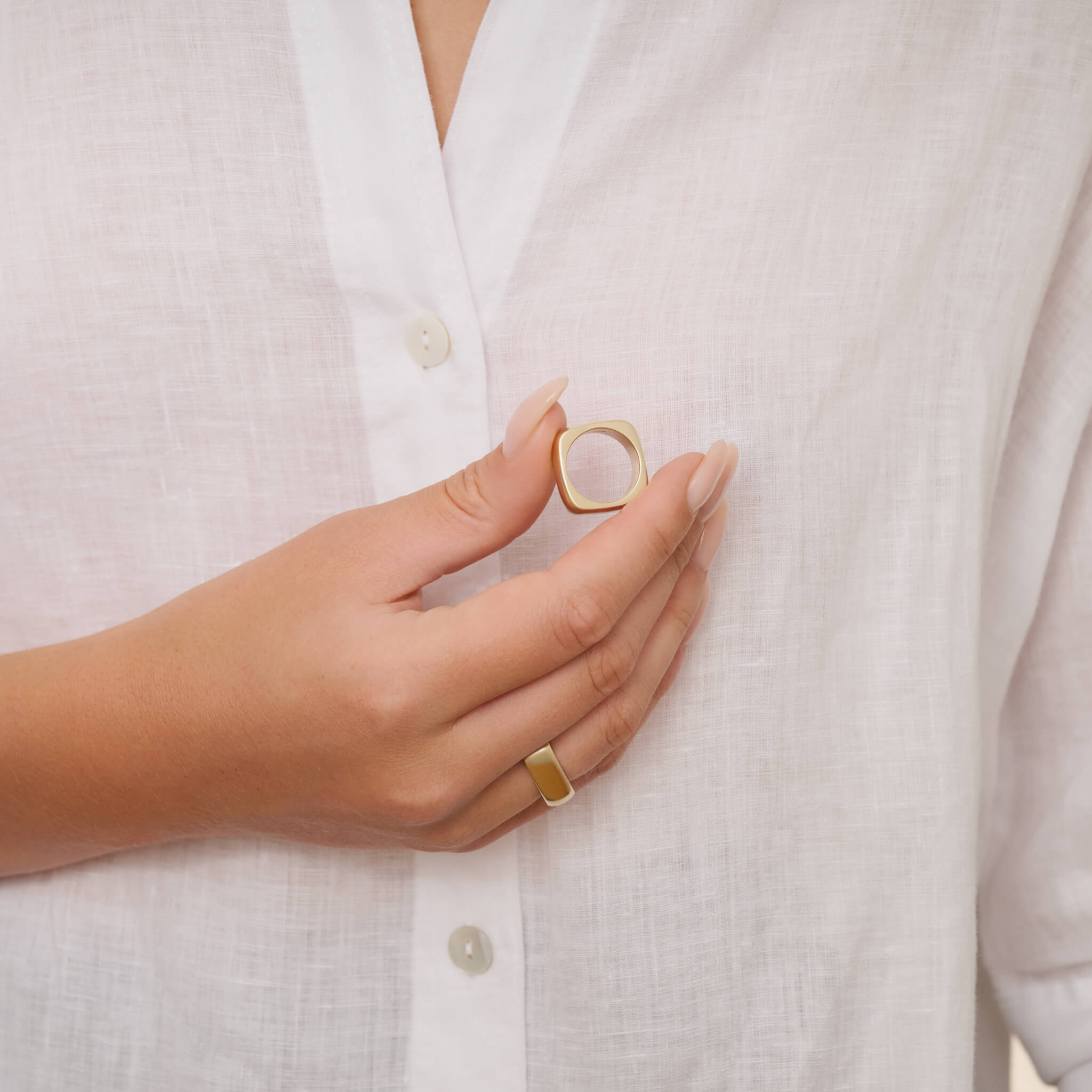 Model wears handcrafted square-shaped ring in 9ct yellow gold with rounded corners inspired by traditional Greek architecture.