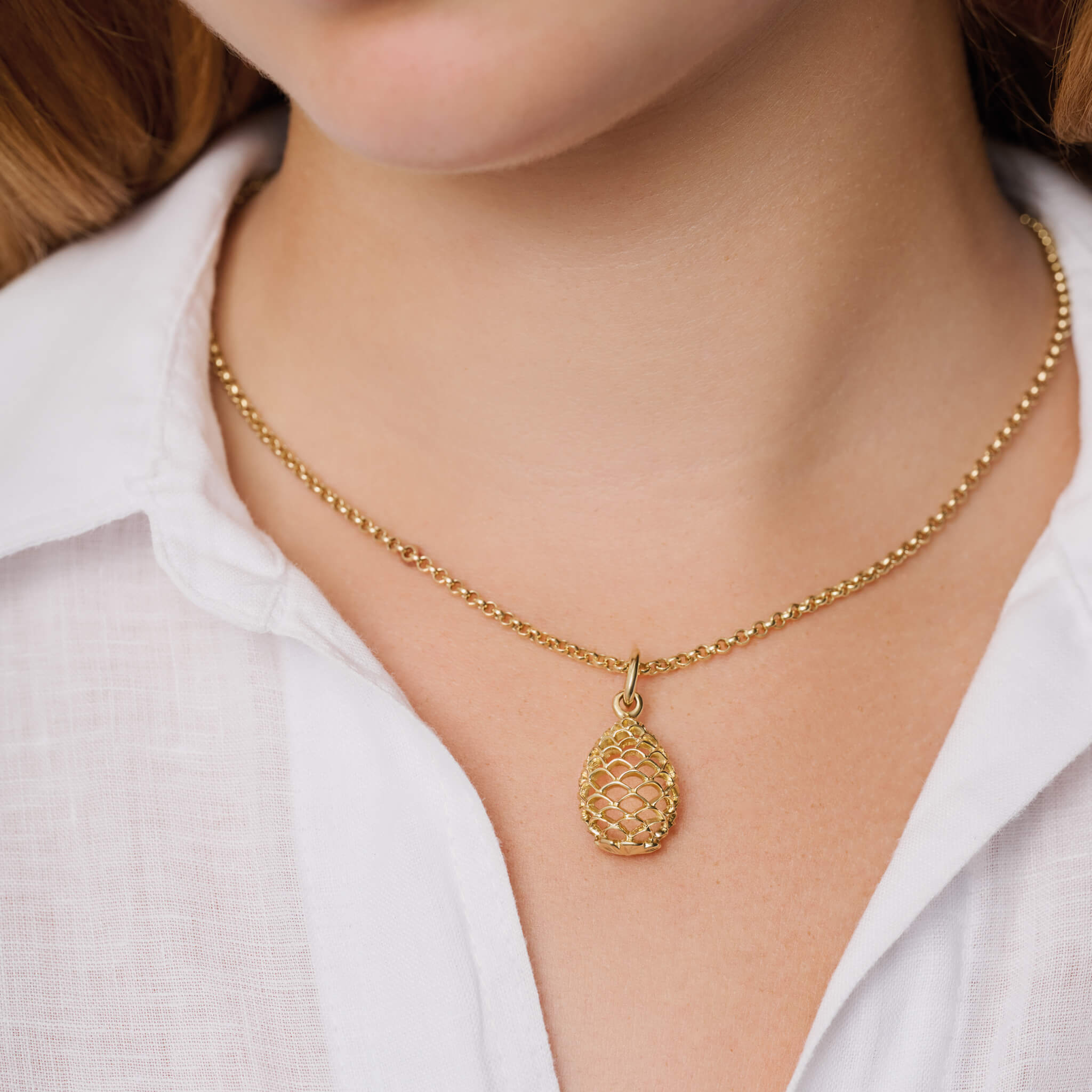 Model wearing handcrafted precious metal necklace pendant featuring a pinecone frame.