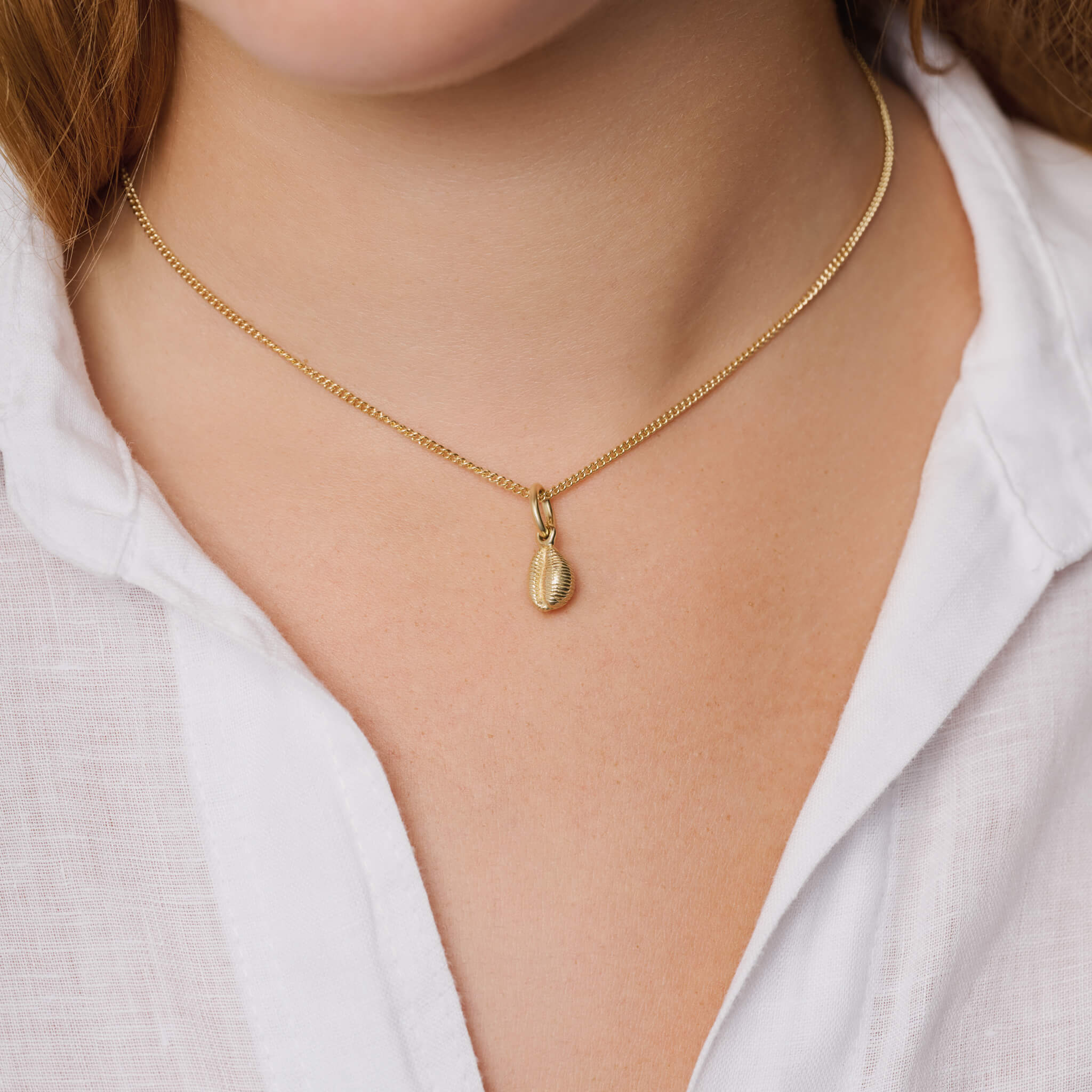 Handcrafted precious metal necklace pendant showcasing a cowrie shell.