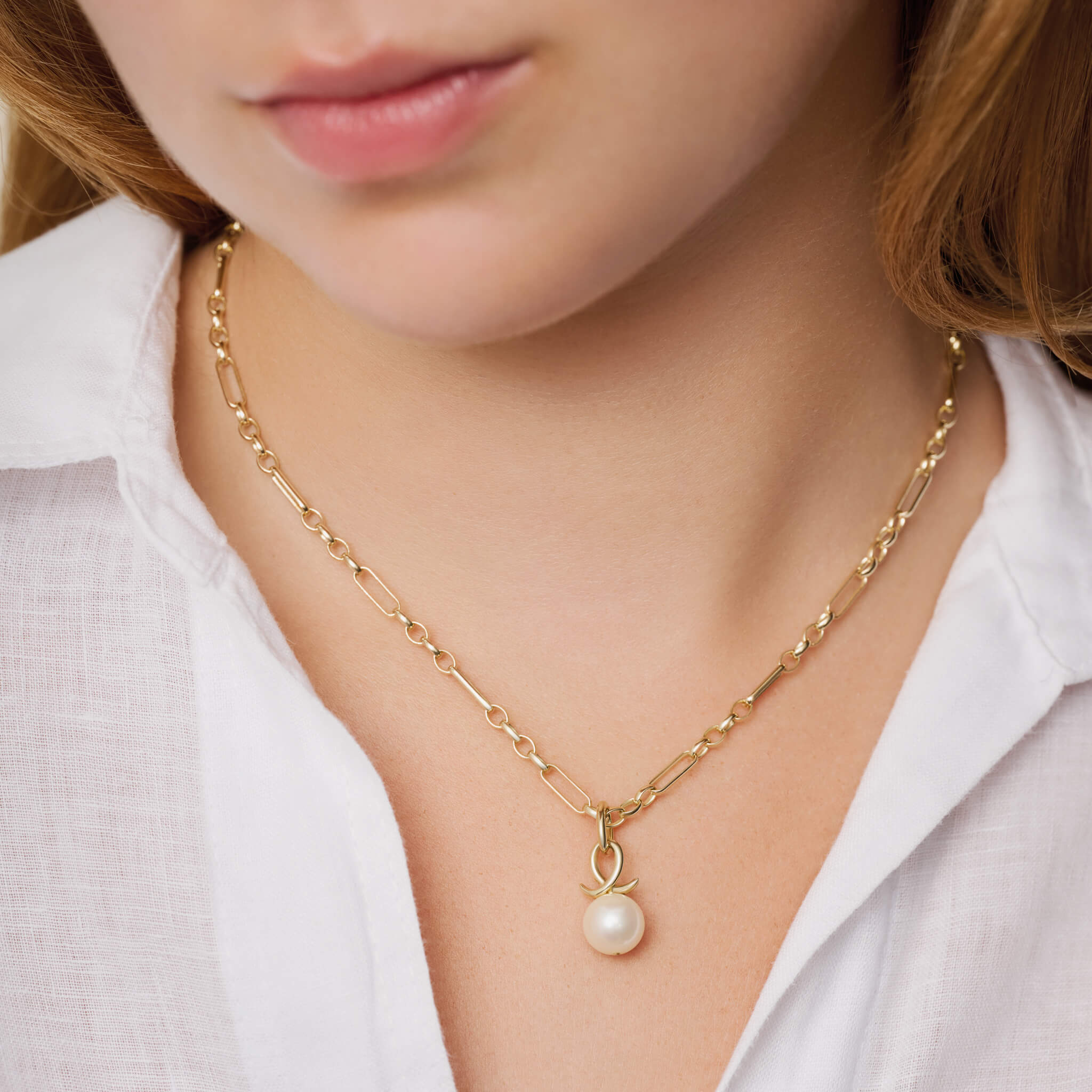 Model wears handcrafted 9ct yellow gold necklace pendant with round pearl and an oval loop shape crossing over.