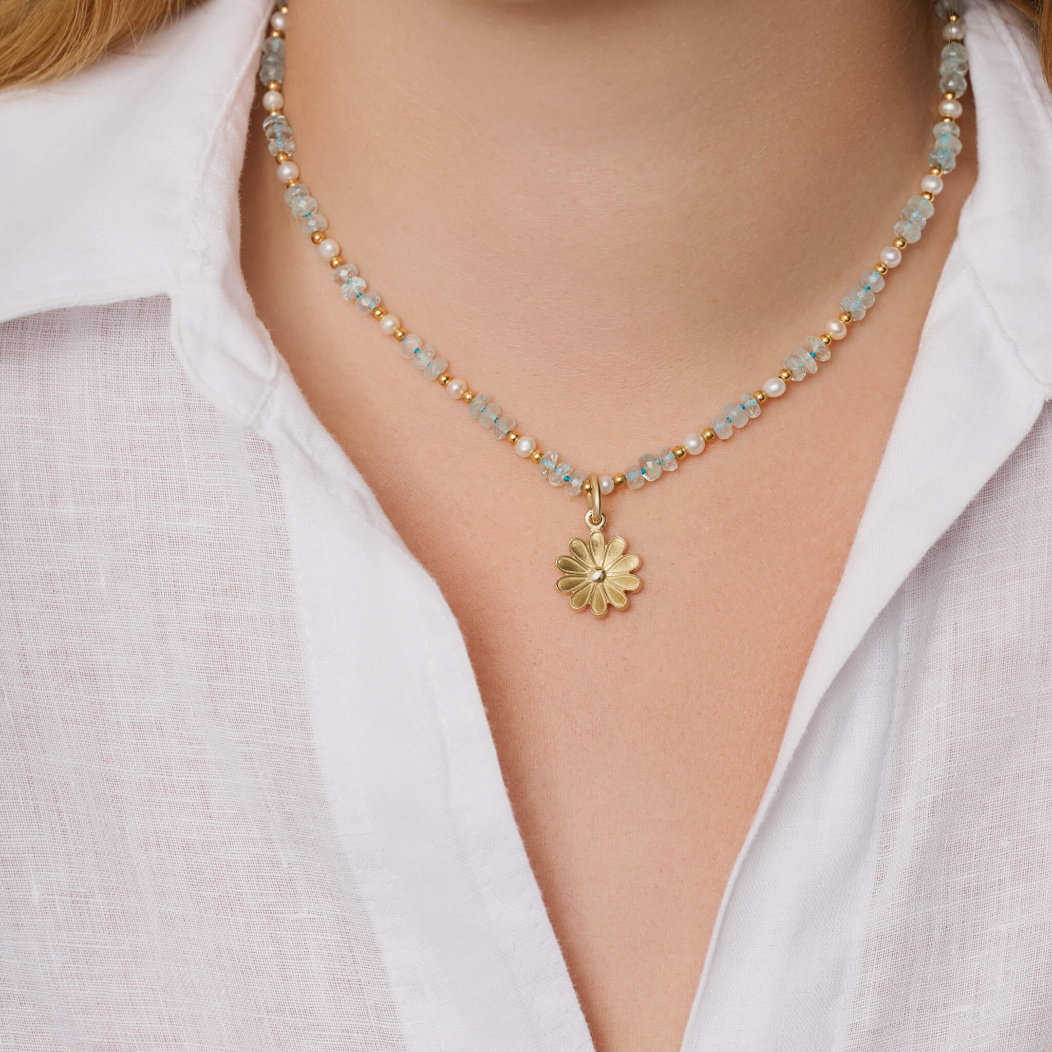 Model wears handcrafted 9ct yellow gold necklace pendant of an anemone flower.