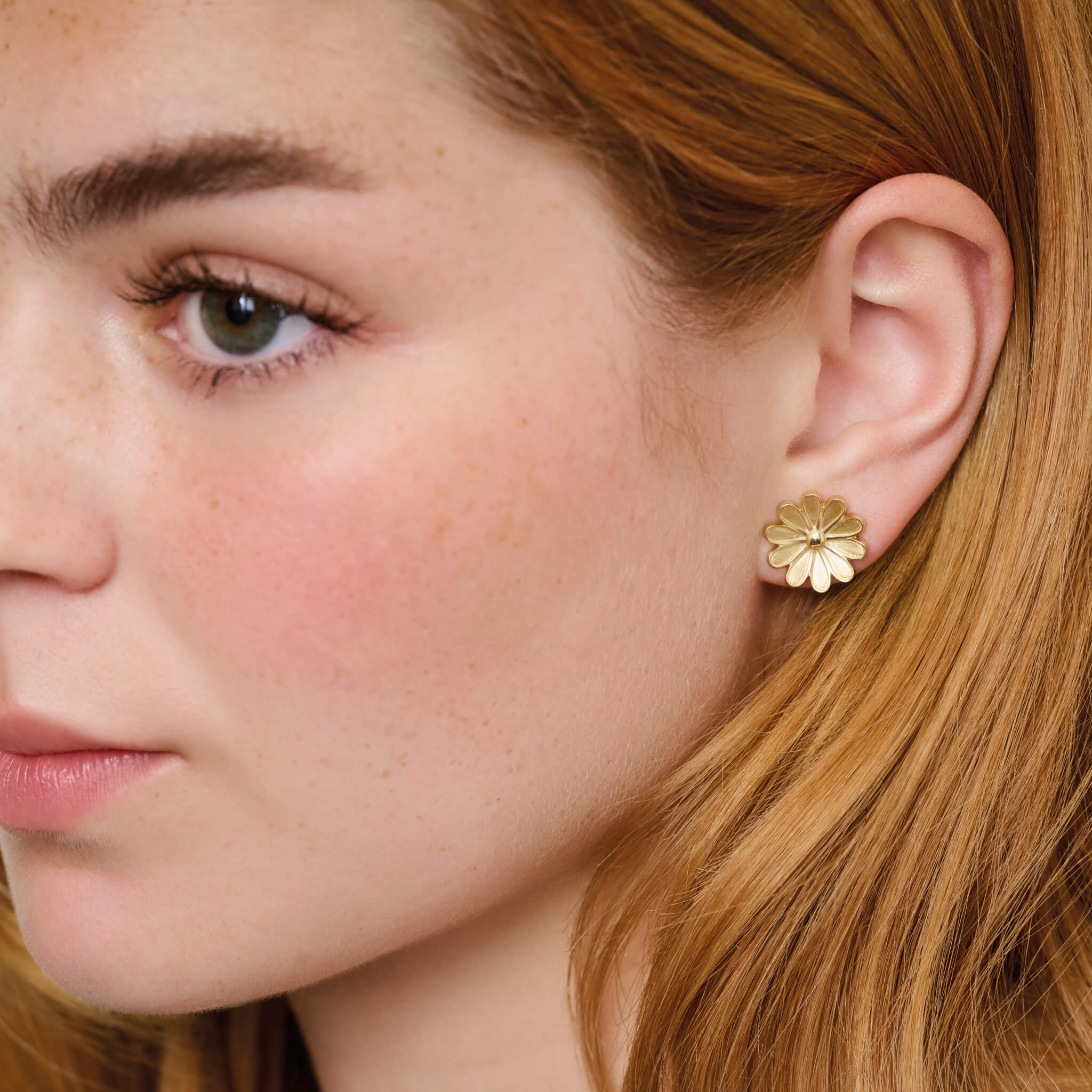 Model wearing handcrafted 9ct yellow gold medium stud earrings of an anemone flower.