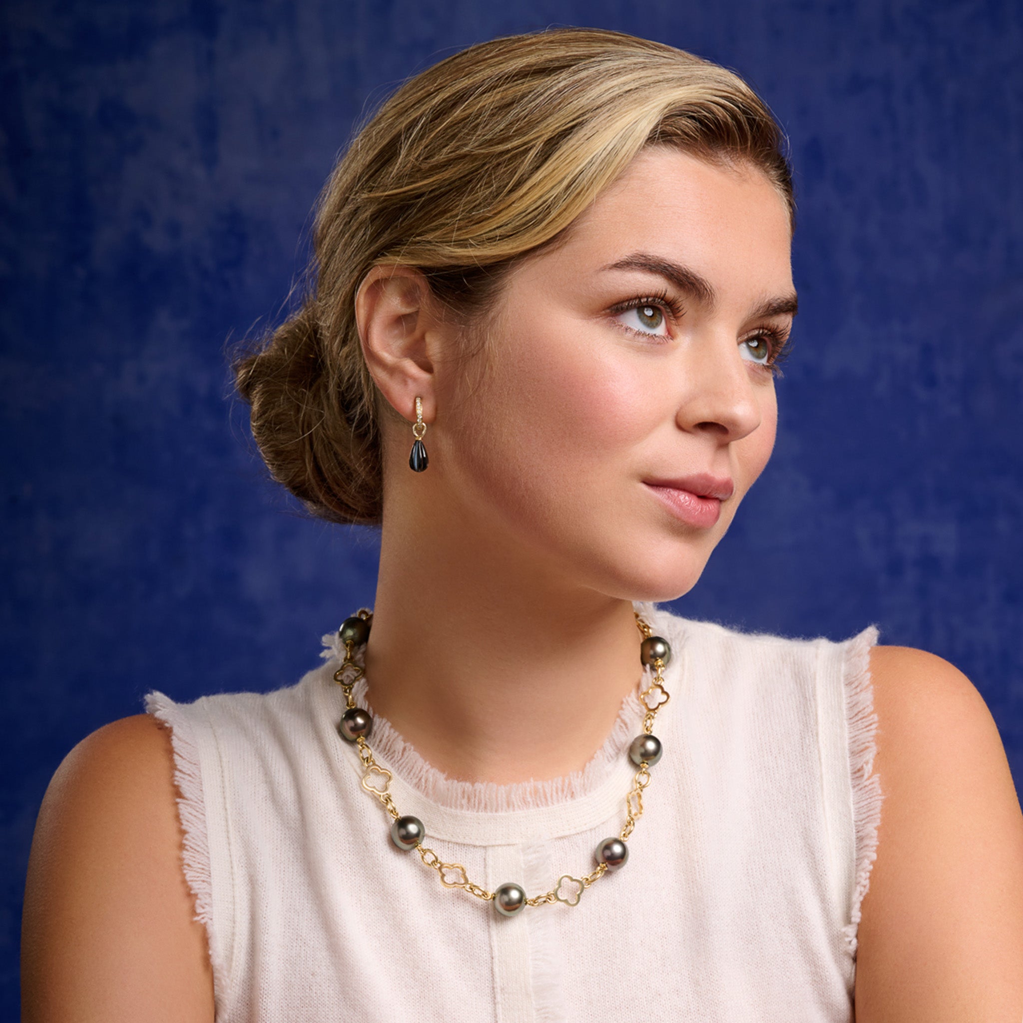 Model wears handcrafted 18ct yellow gold necklace with alternating tahitian pearls and pierced gold motifs in the shape of a flower.