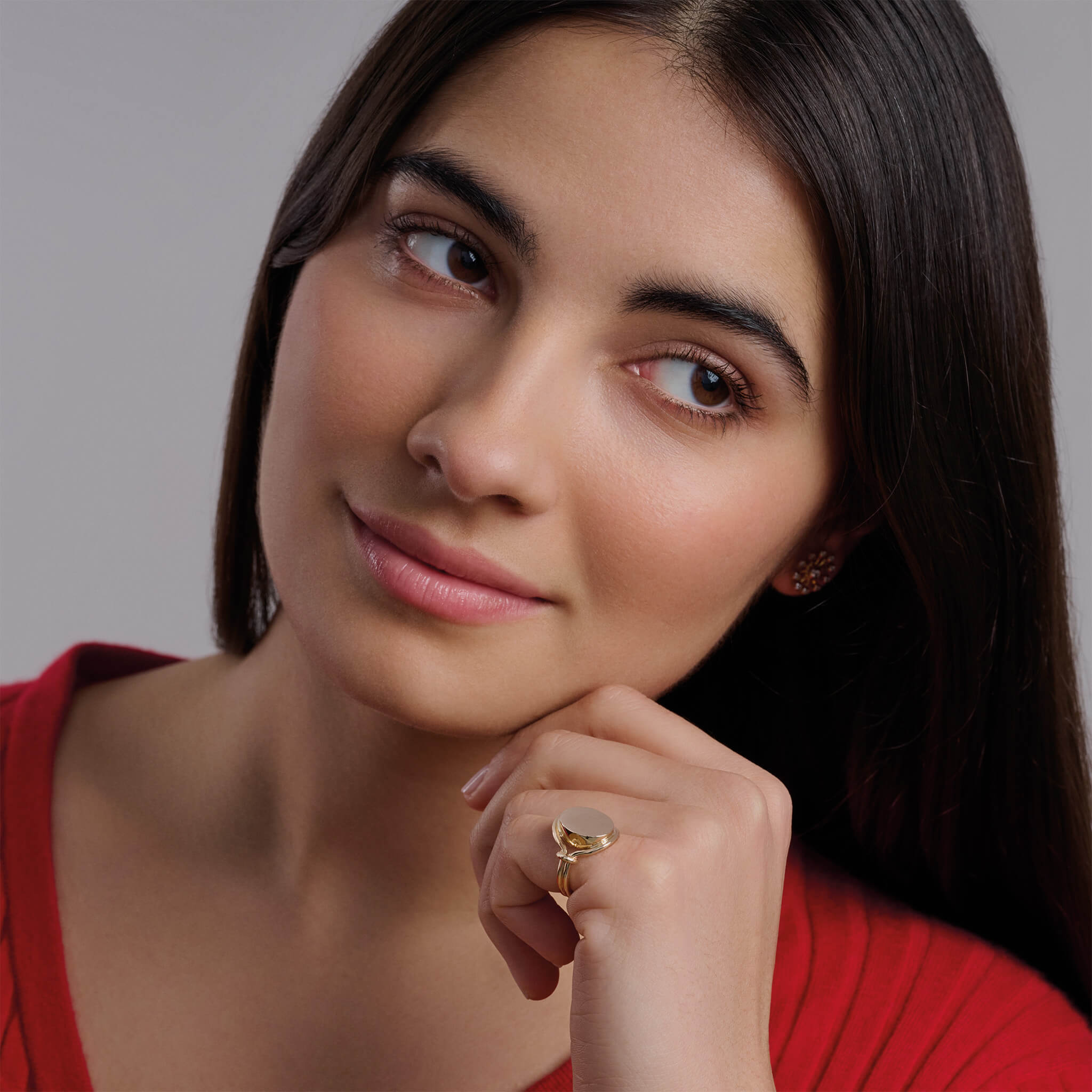 Model wearing a handcrafted yellow gold signet ring featuring a smooth, round central disc with sleek, curved band accents.