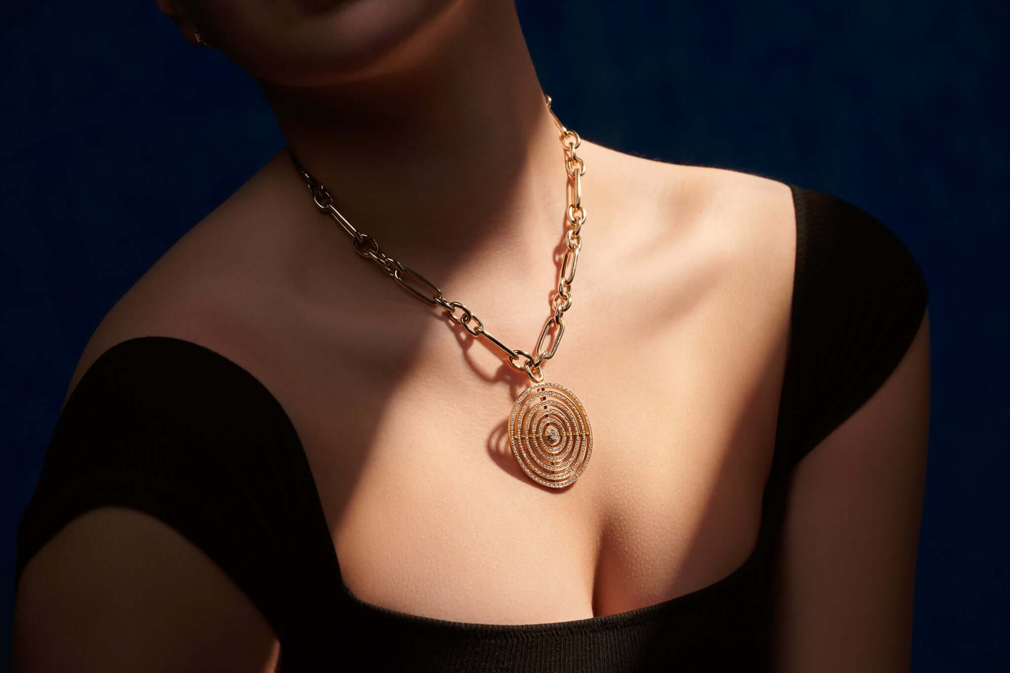 Model wearing a handcrafted 18ct yellow gold necklace pendant featuring five circles of gold with diamonds.