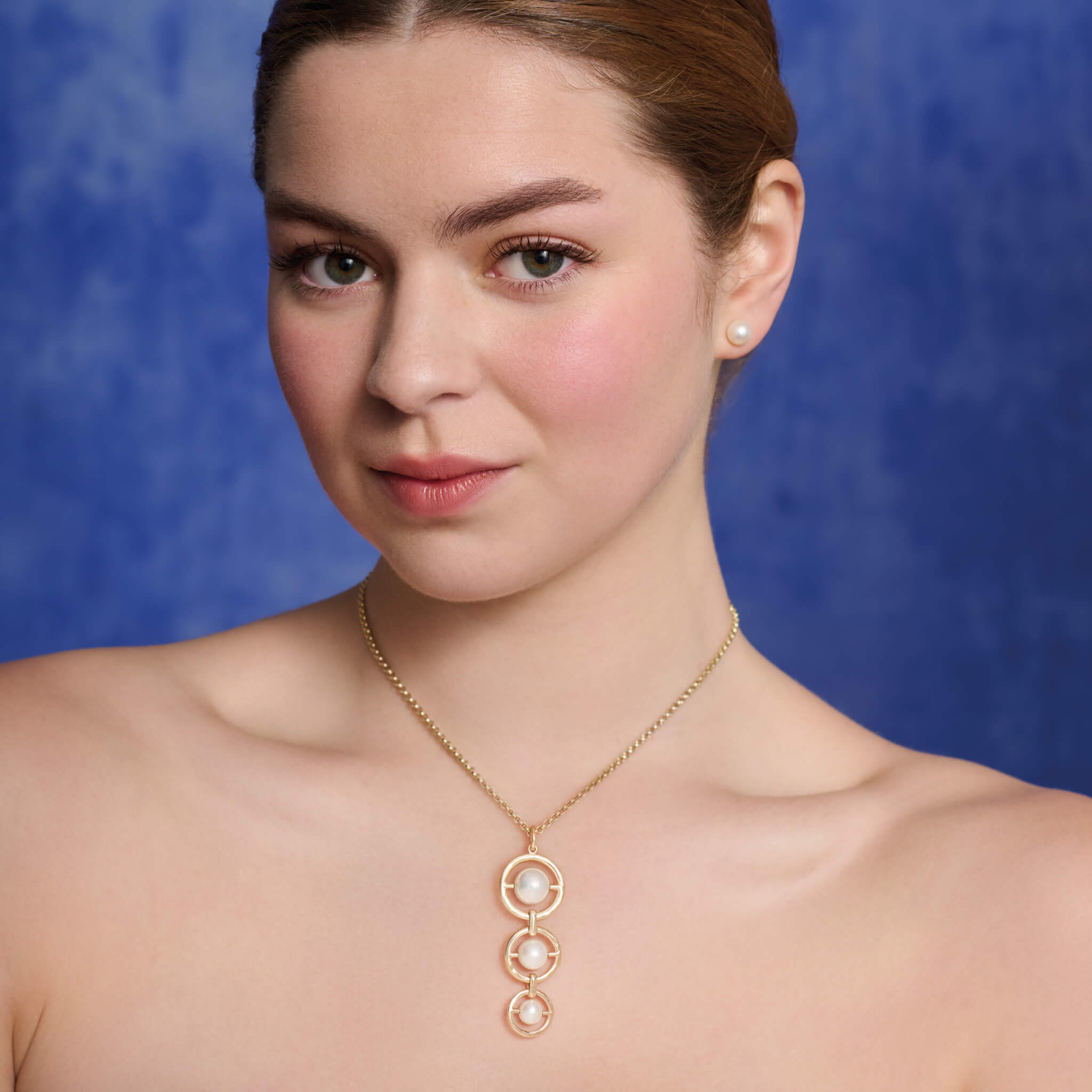 Model wears Cassandra Goad Archipelago Triple necklace pendant in yellow gold and pearl.