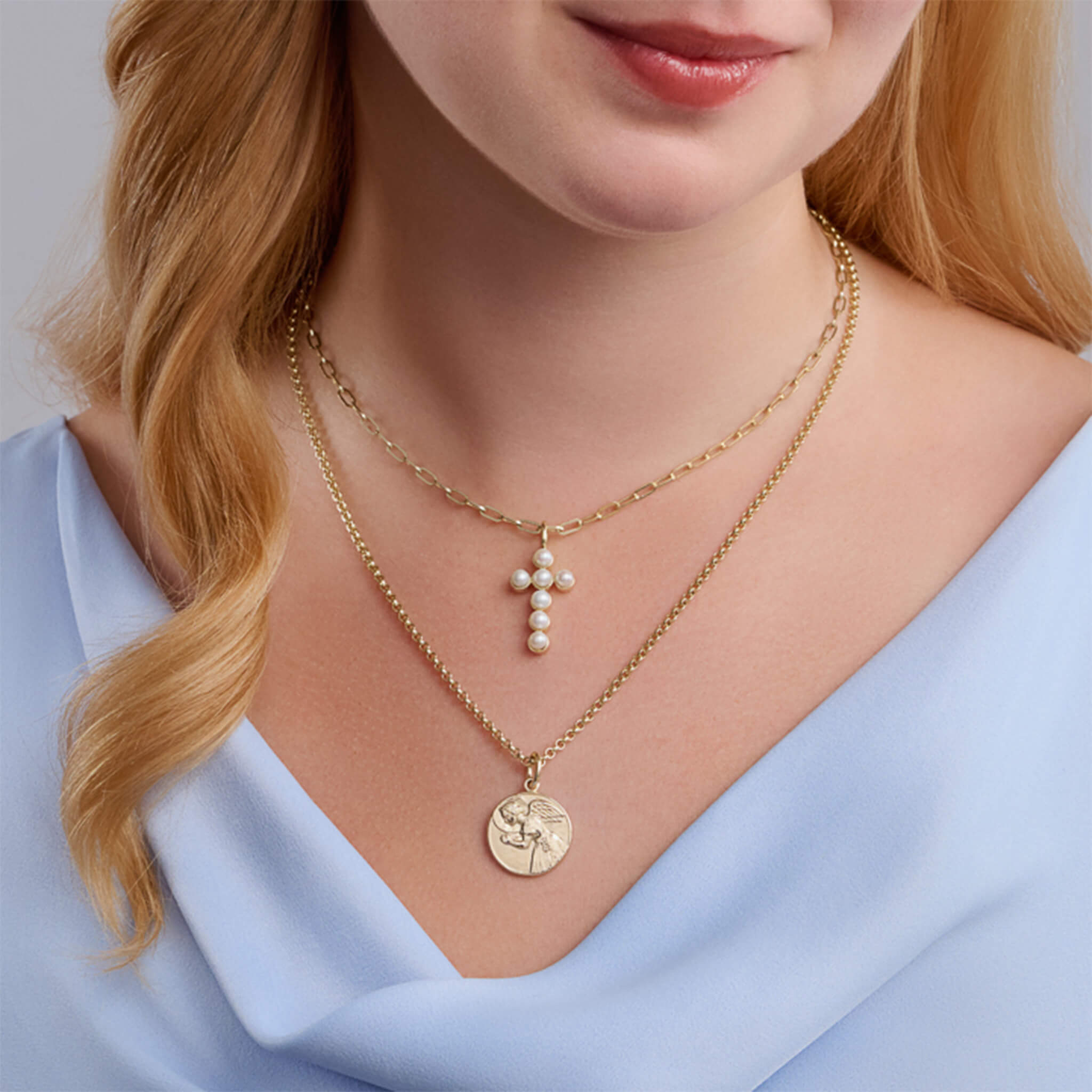 Handcrafted cross in yellow gold set with pearls, birthstone of June, hanging from a necklace chain.