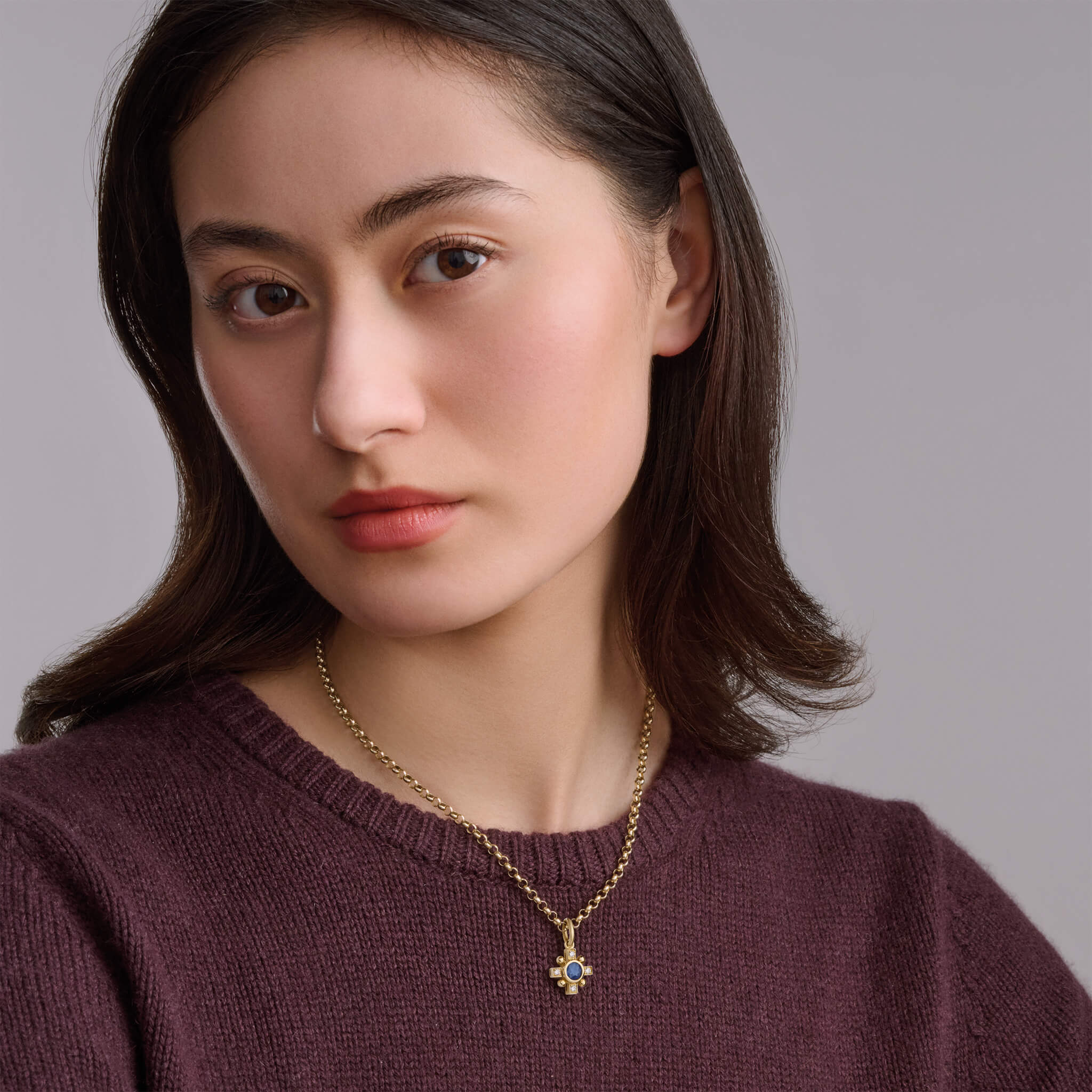 Handcrafted Quadro cross necklace pendant in yellow gold featuring a central blue sapphire and diamond, september birthstone