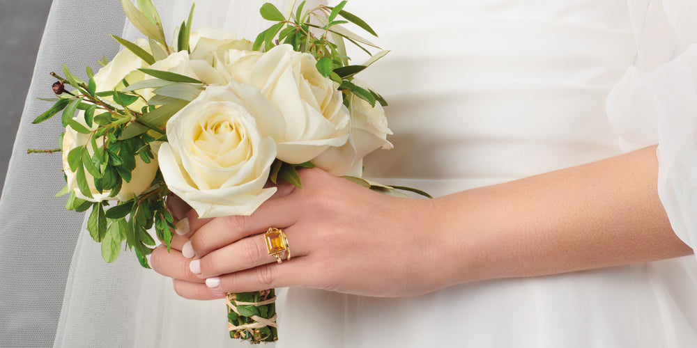 Bride holding bouquet of flowers wearing a citrine baguette cut yellow gold engagement ring