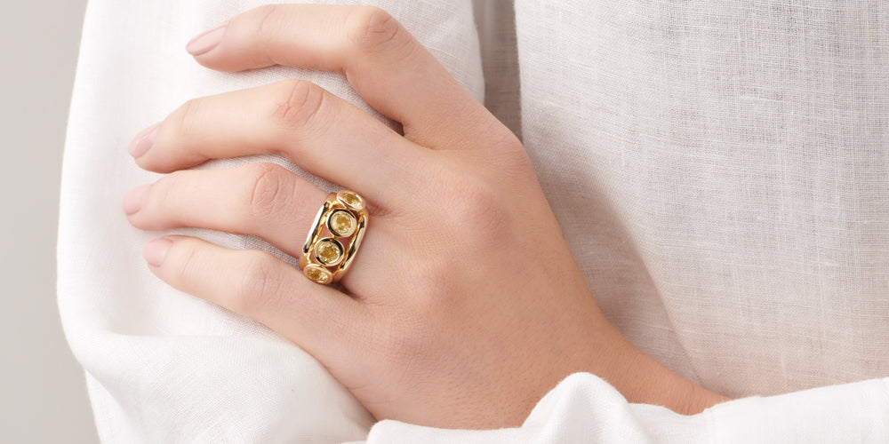 Model wearing a handcrafted yellow gold ring featuring four round citrines, birthstone of November.