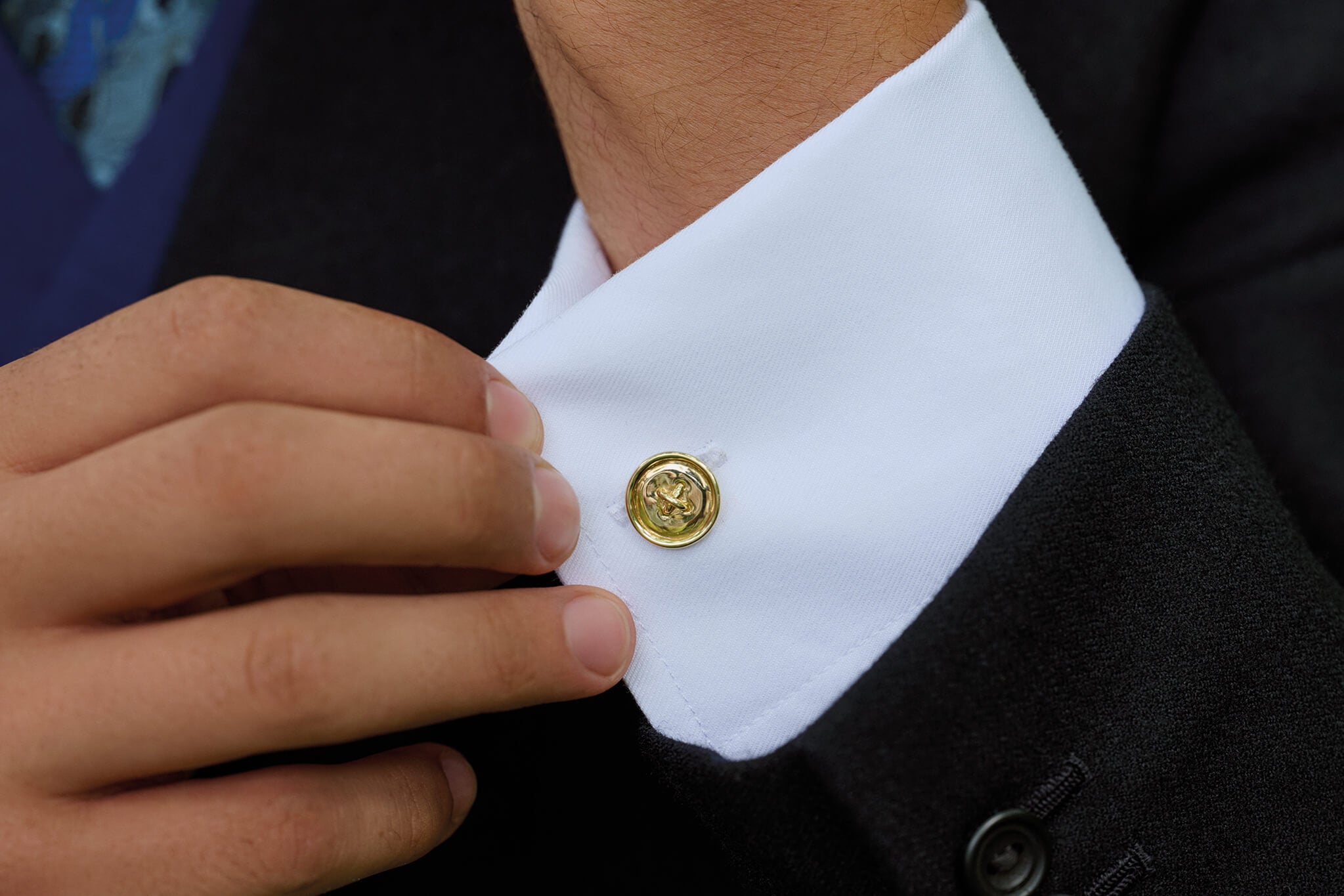 Model wearing handcrafted yellow gold cufflinks on a white shirt.