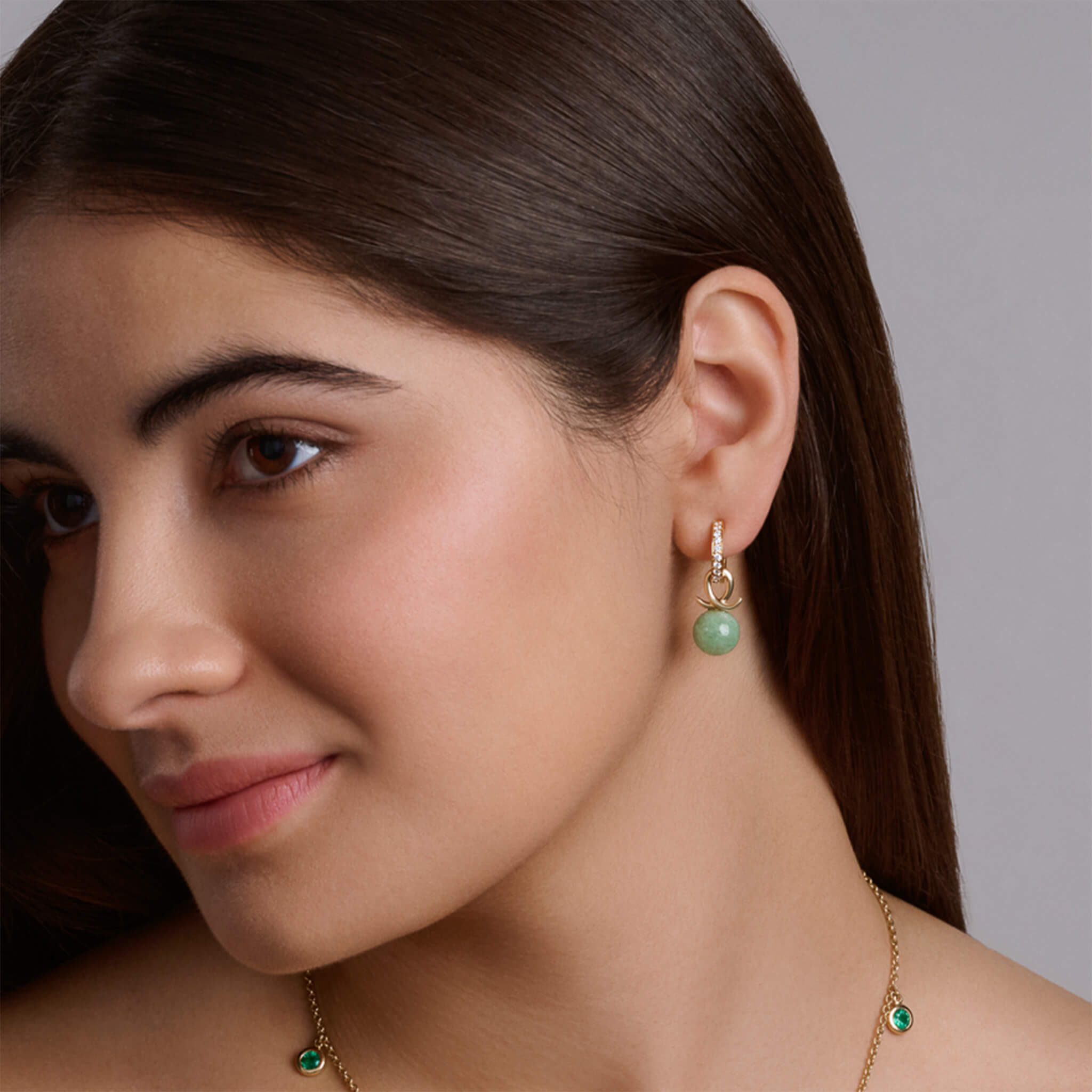 Handcrafted 9ct yellow gold earring drops with round mottled emerald and an oval loop shape crossing over.
