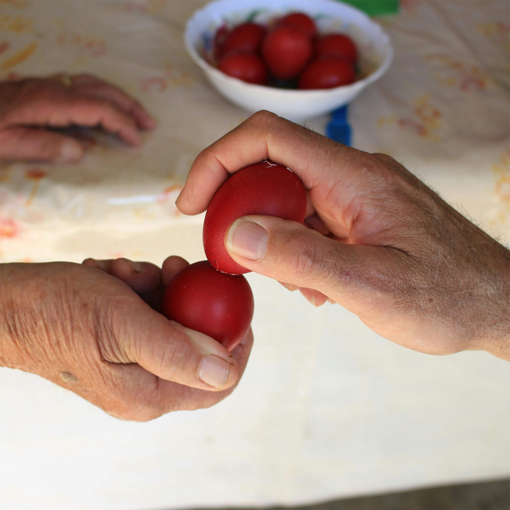 Two hands breaking red eggs as a Greek Easter tradition. 