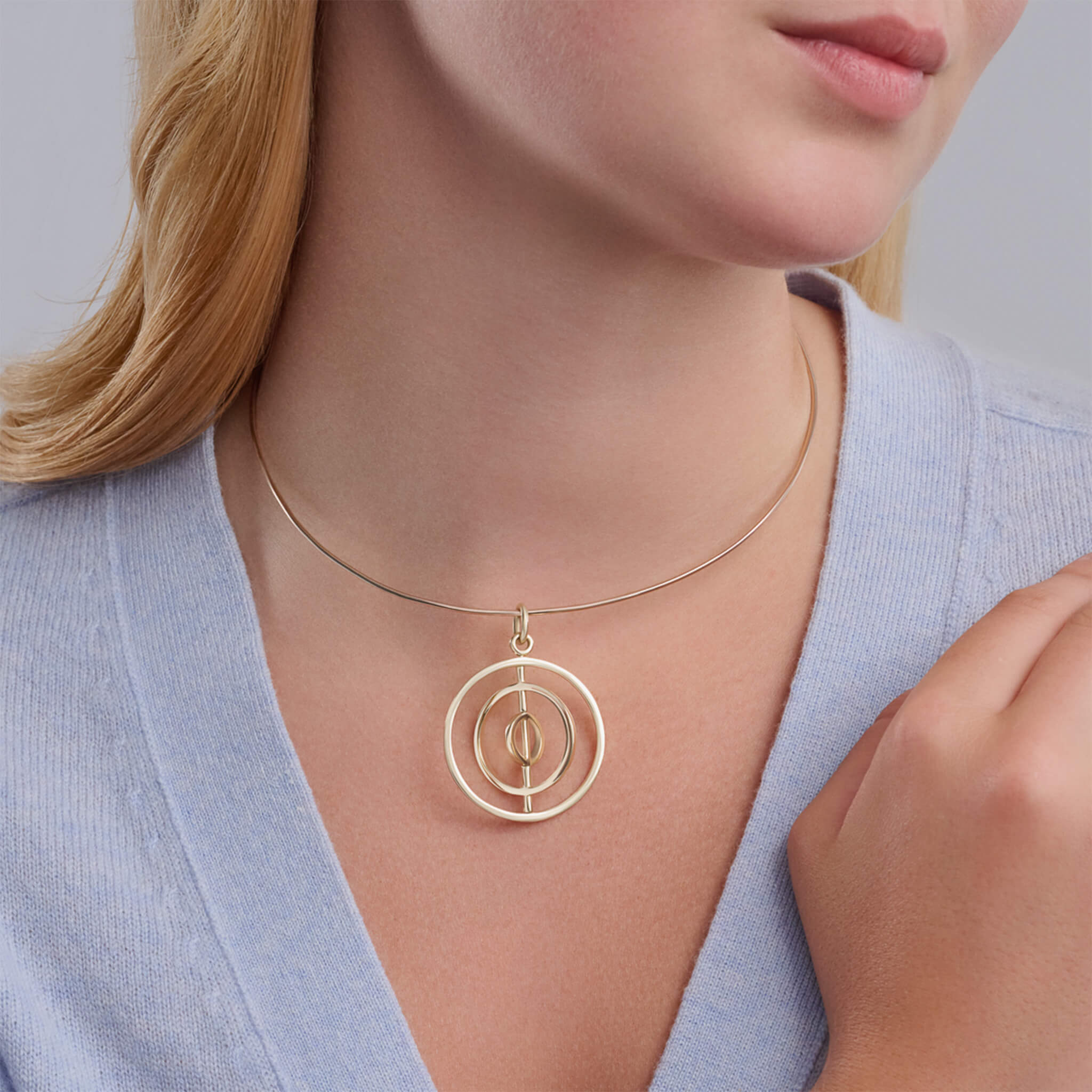 Handcrafted yellow gold necklace pendant featuring three circles around central axis.
