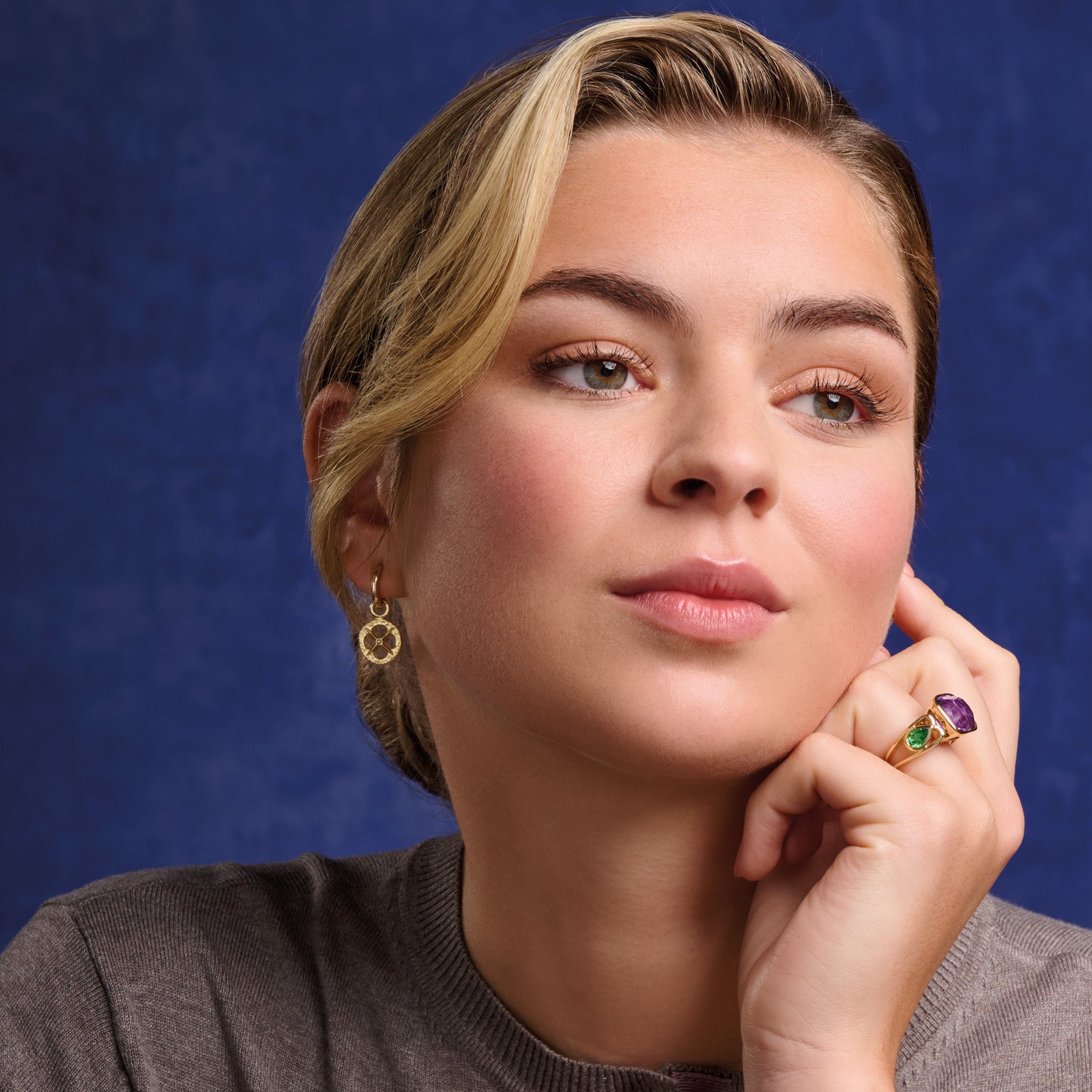 Model wearing handcrafted precious metal earring drops with a circular motif and a cross in the middle.