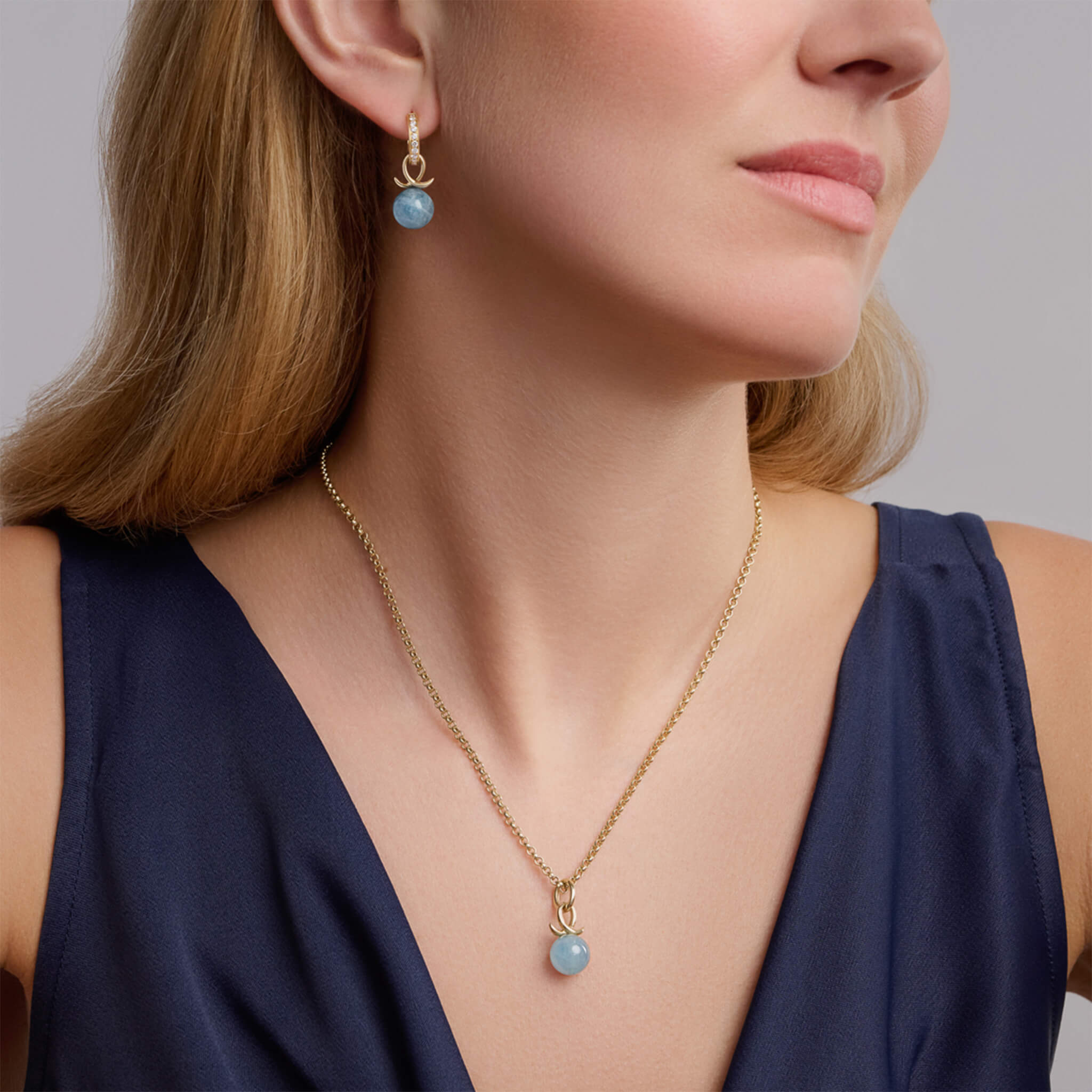 Handcrafted 9ct yellow gold earring drops with aquamarine bead and an oval loop shape crossing over.