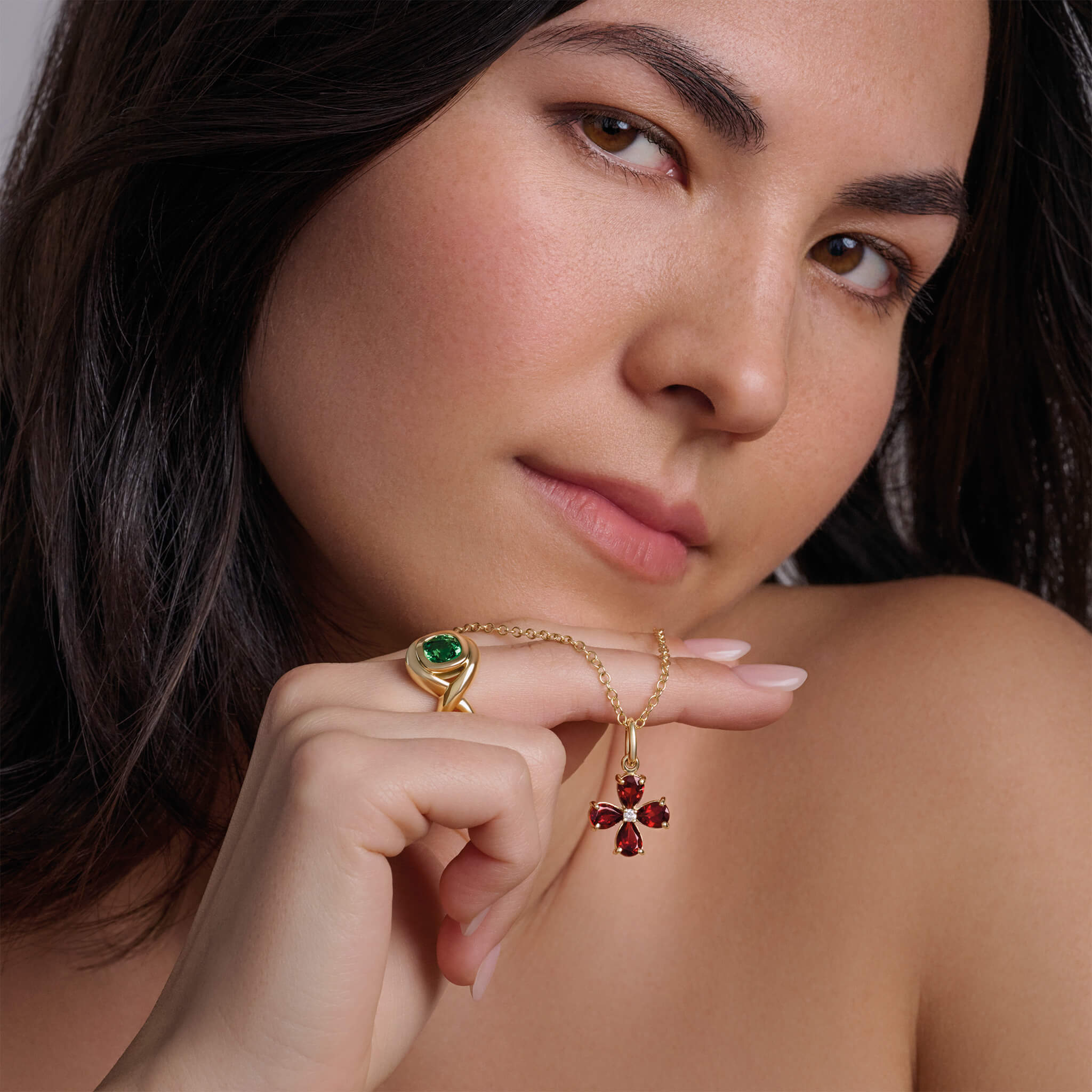 Model wearing a handcrafted yellow gold four-leaf clover necklace pendant with precious stones.