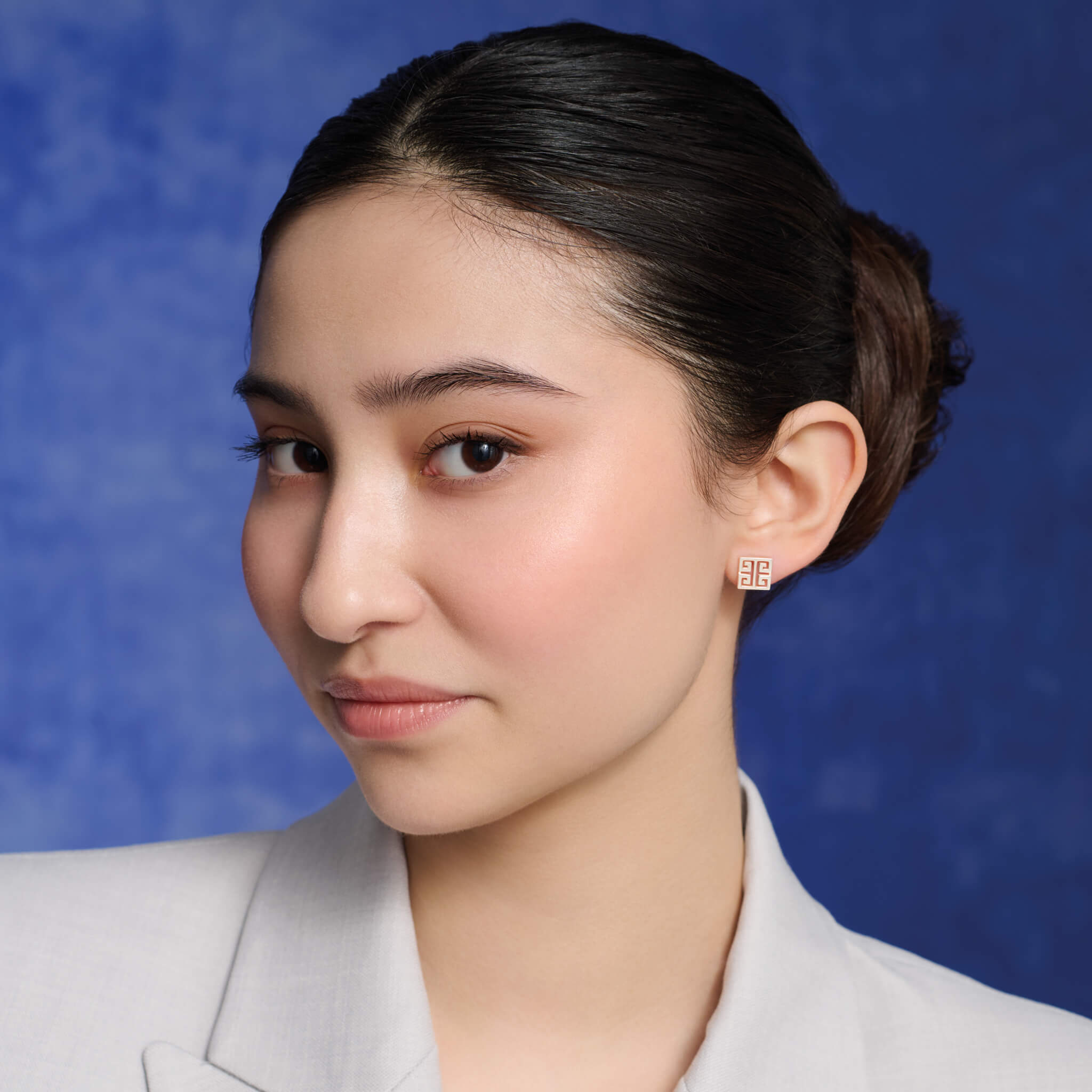 Model wearing handcrafted square stud earrings with iconic symmetrical Greek motif.