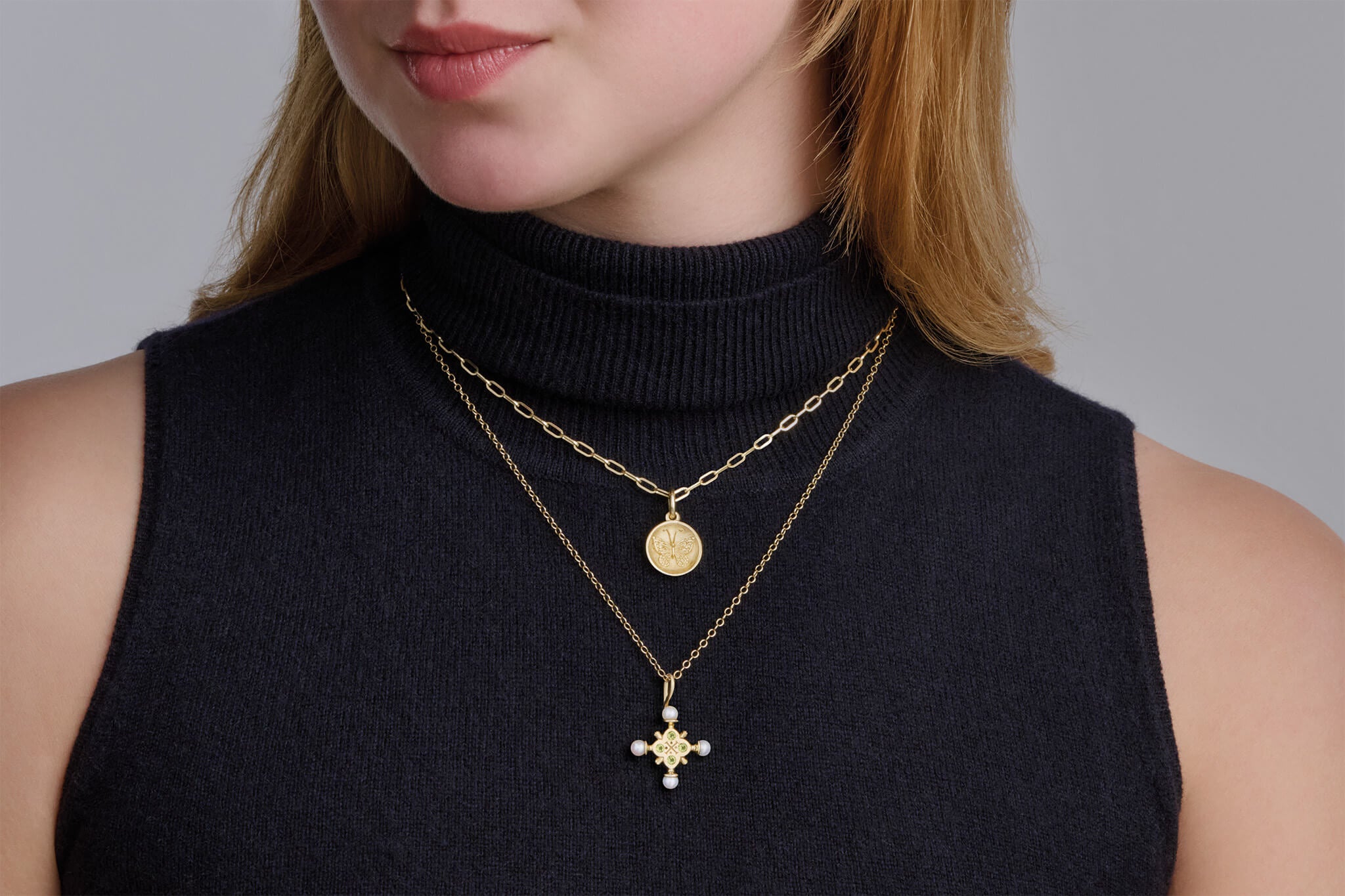Model wearing medallion charm and madrid cross with peridot layered.