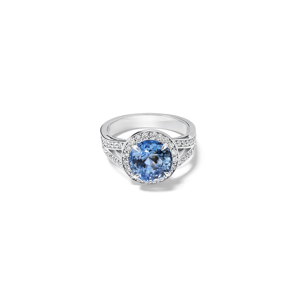 Handcrafted 18ct white gold engagement ring with a large round central blue sapphire surrounded by a halo of small diamonds and smaller diamonds embedded along the band.