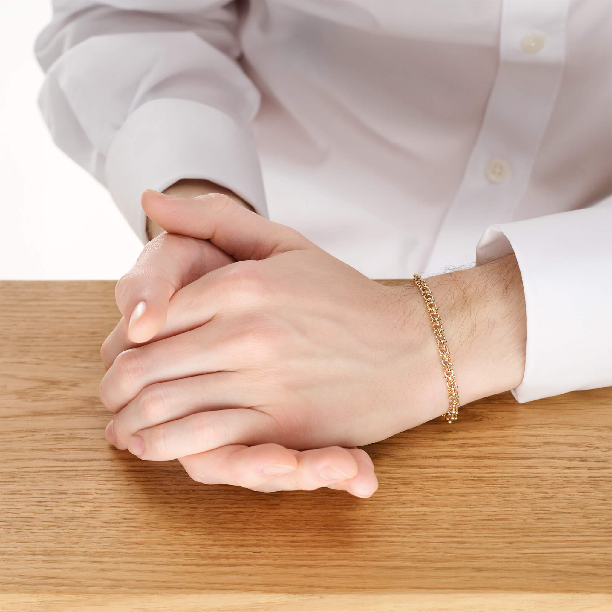 Model wears handcrafted yellow gold bracelet with links and small beads.